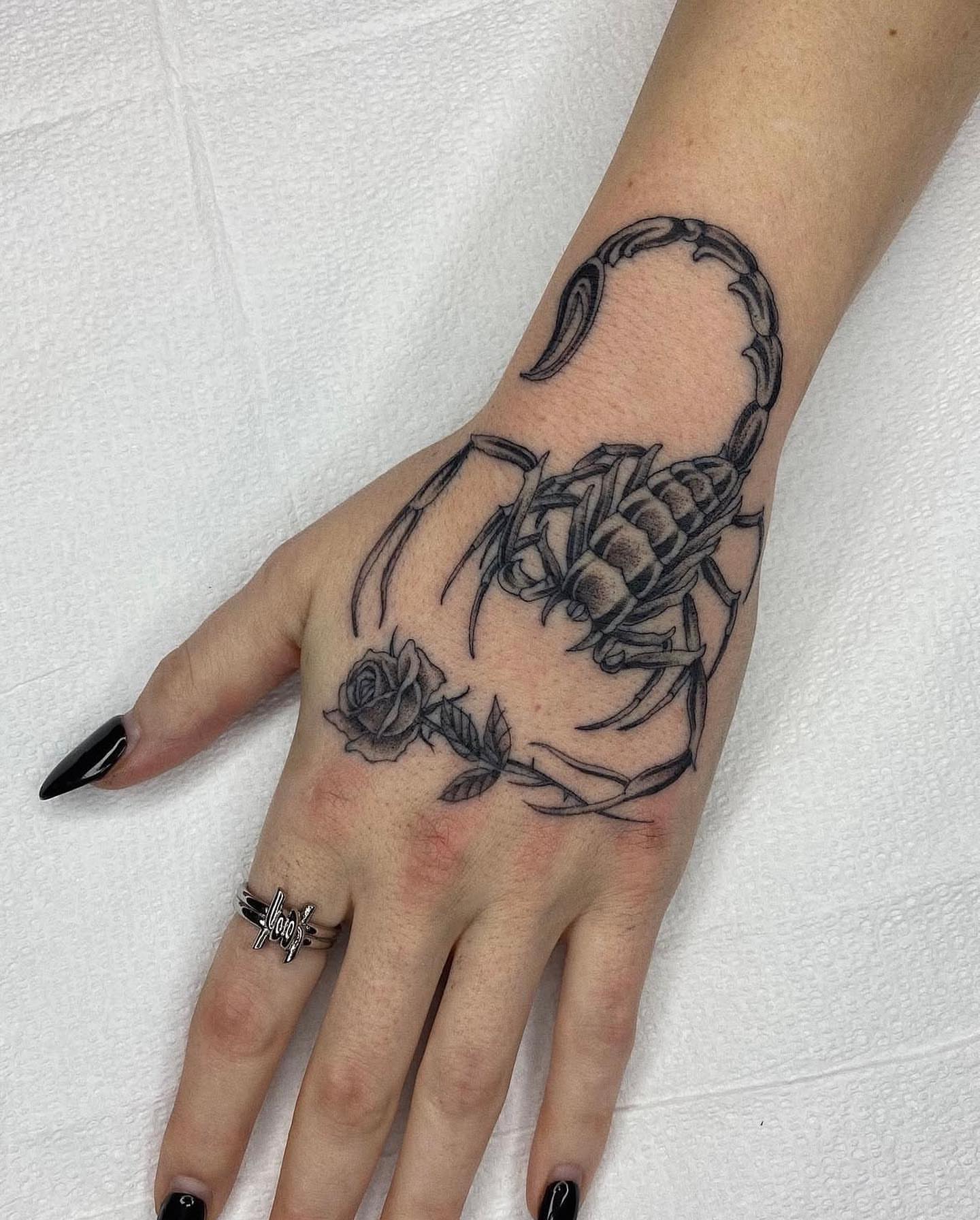 Scorpion and rose black and grey tattoo on the hand by Finley Jordan
