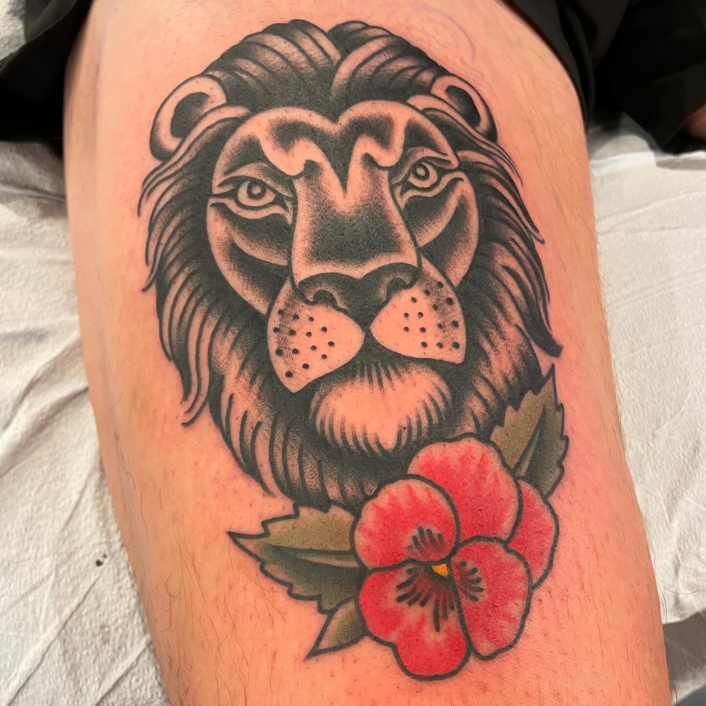 Lion head with pansy American traditional tattoo on the thigh by Grandma Approved, Chicago, Illinois