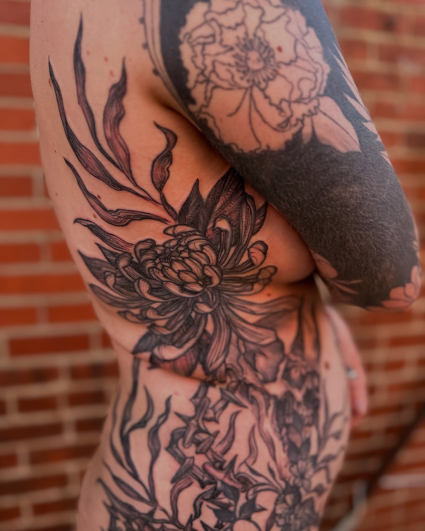 Floral design black and grey tattoo on the thigh by Benjamin Carlson