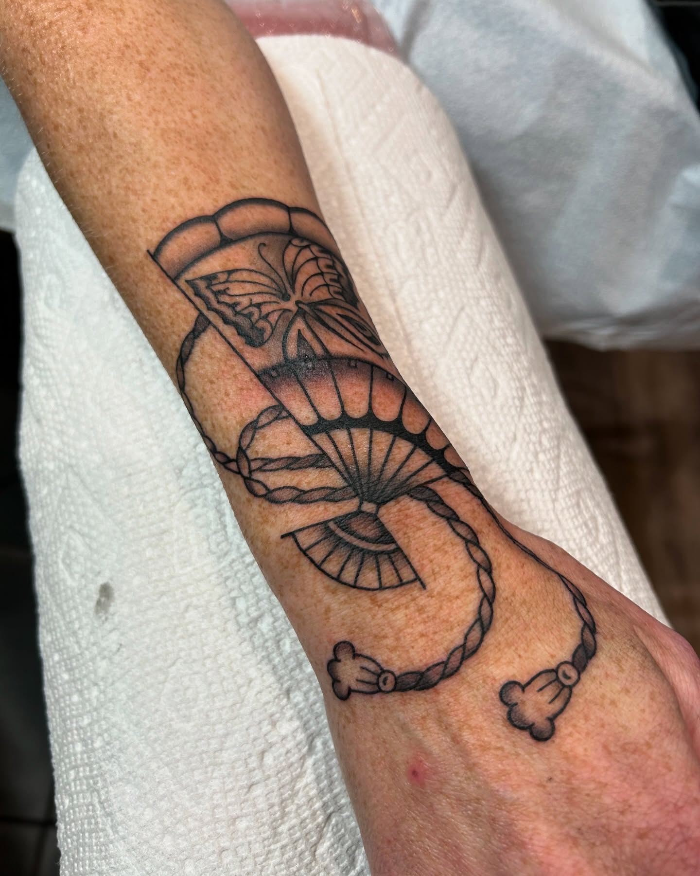 Butterfly and fan black and grey tattoo on the forearm by Lilly Binns