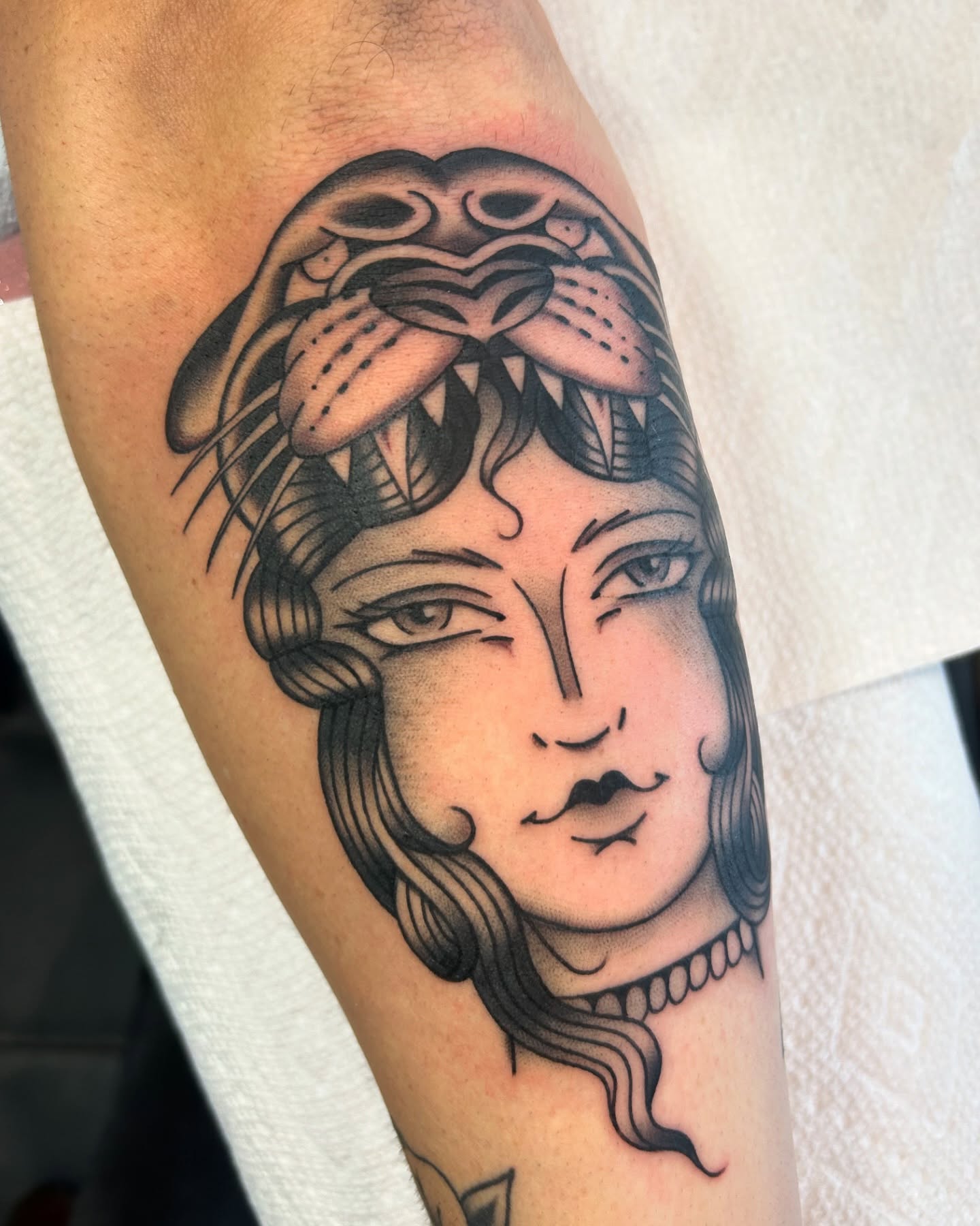 Woman's head with lion American traditional tattoo on the forearm by Lilly Binns