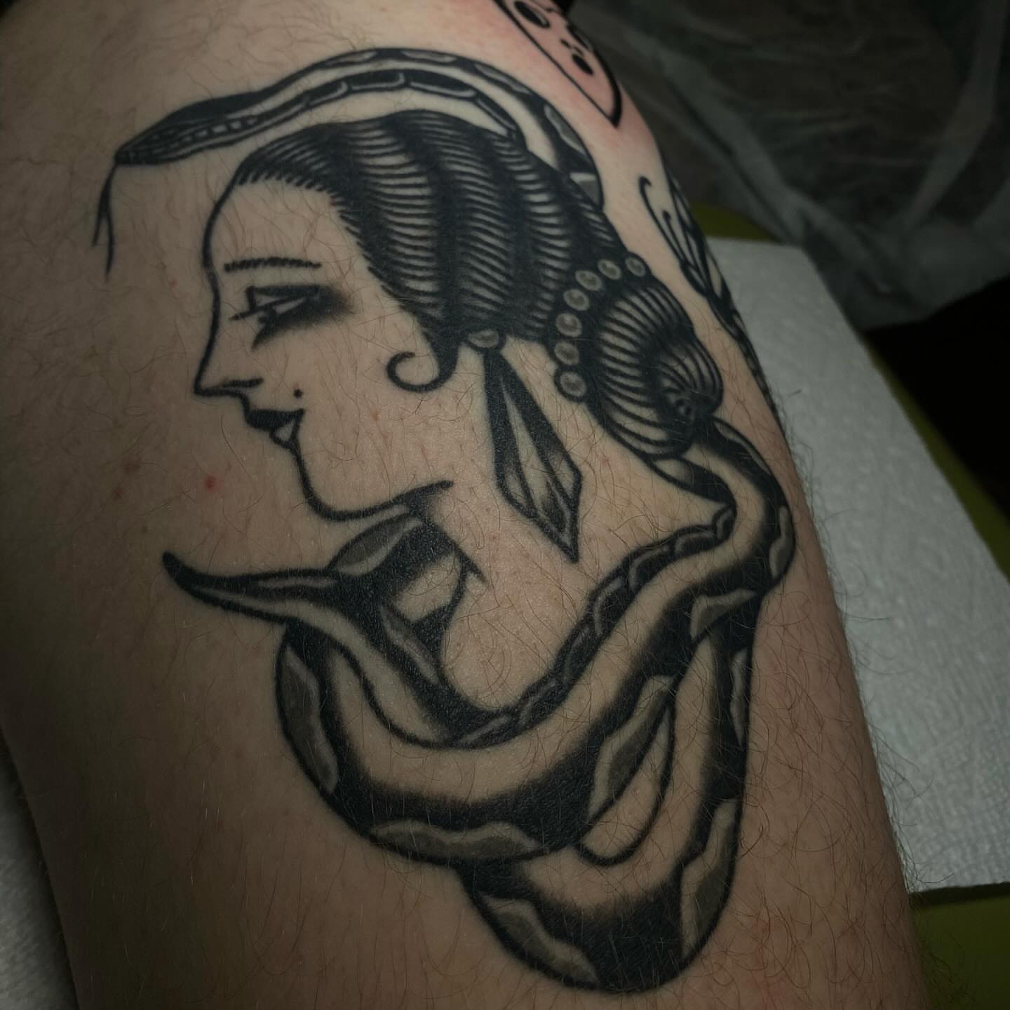 Woman with snake black and grey tattoo on the upper arm by Erin Chambers