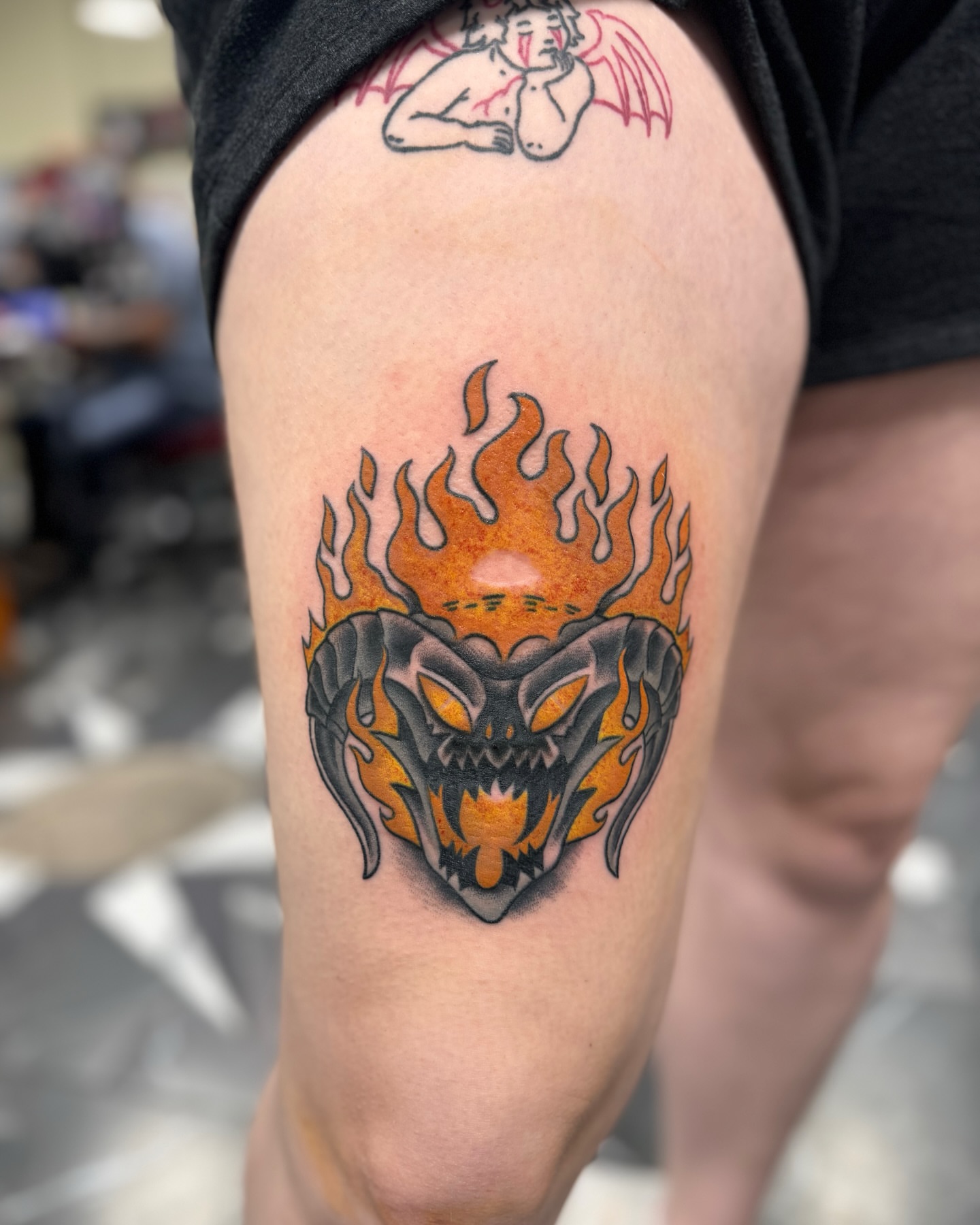 Flaming demon head American traditional tattoo on the thigh by Suda
