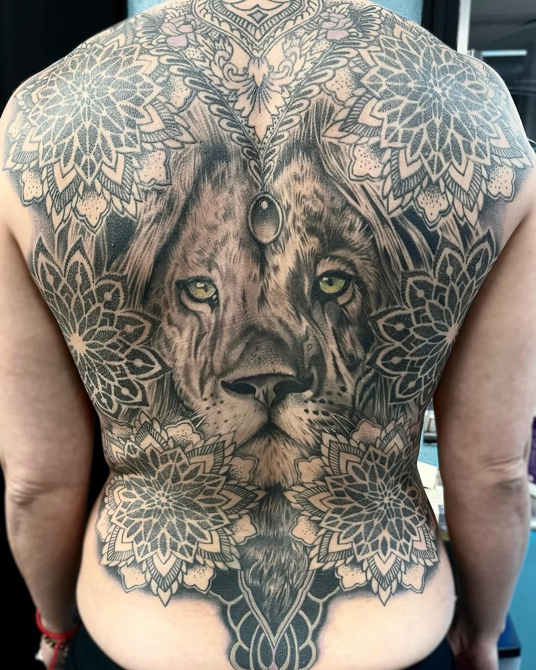 Lion face with mandala patterns geometric tattoo on the back by Sacramento Tattoos (Ilona)