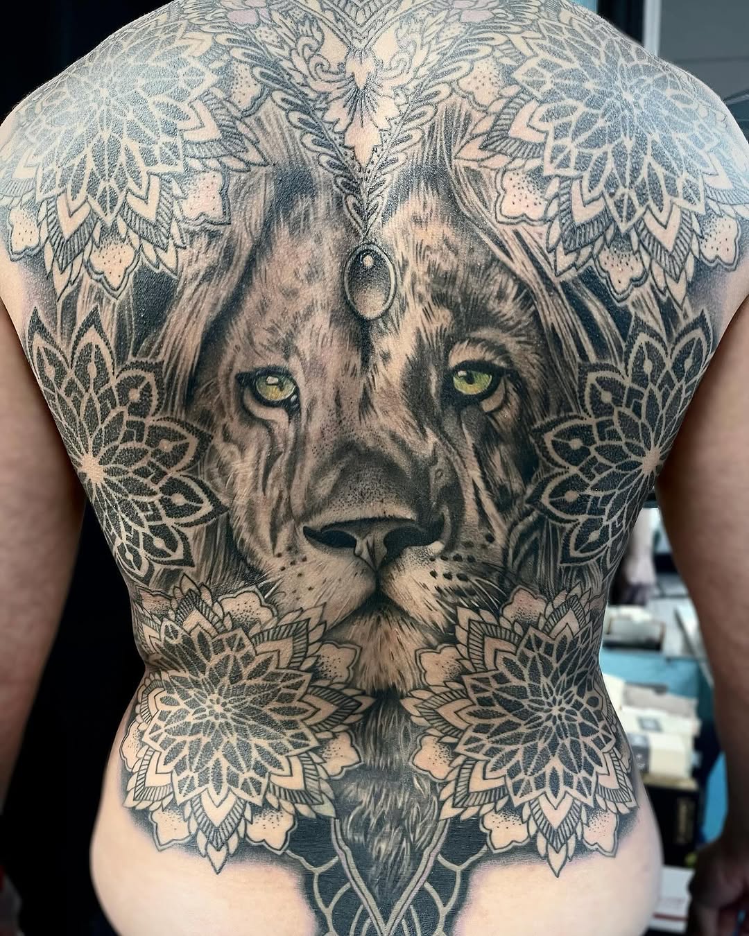 Lion face with mandala patterns geometric tattoo on the back by Sacramento Tattoos (Ilona)