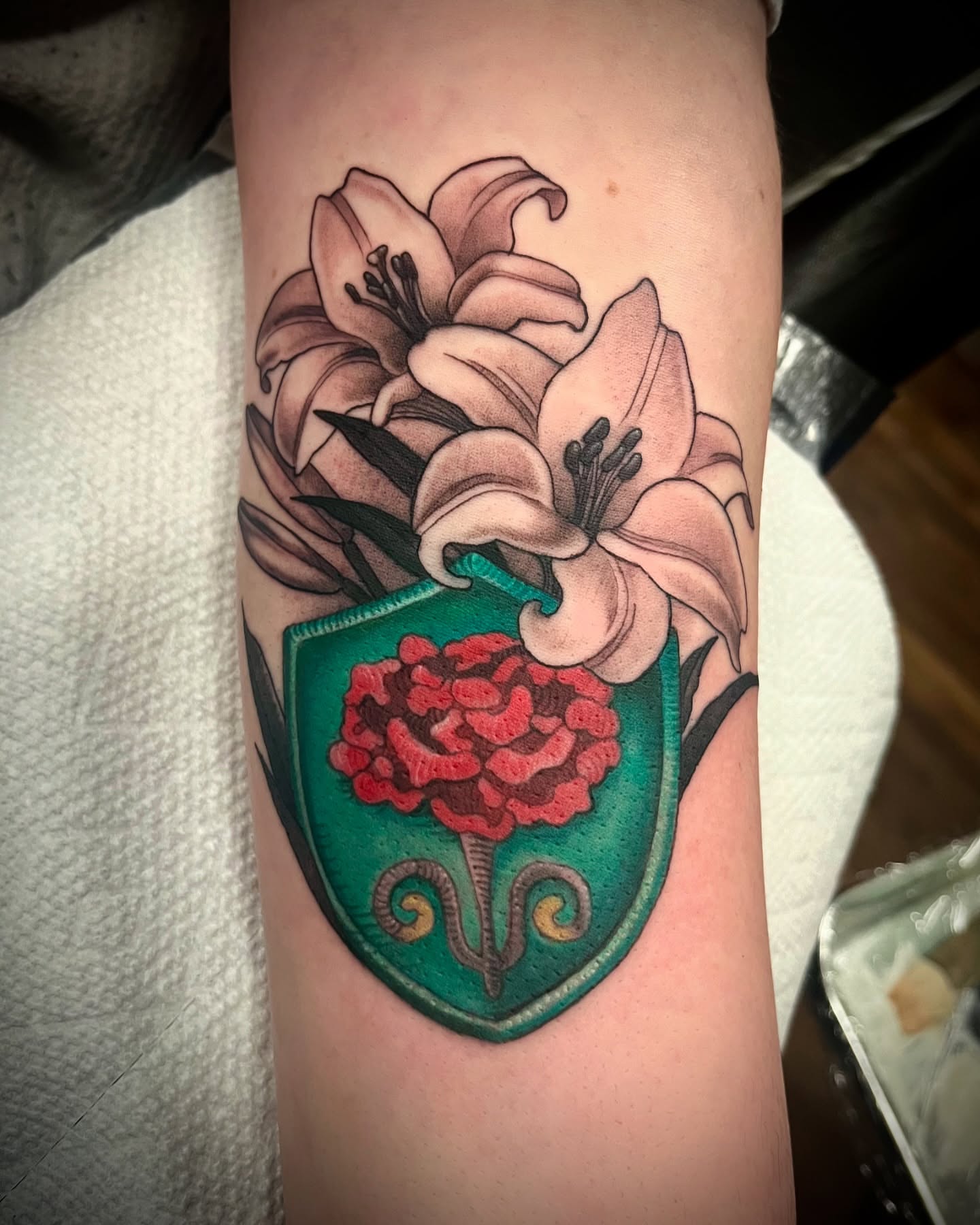 Lilies and shield American traditional tattoo on the forearm by Jessica Brown