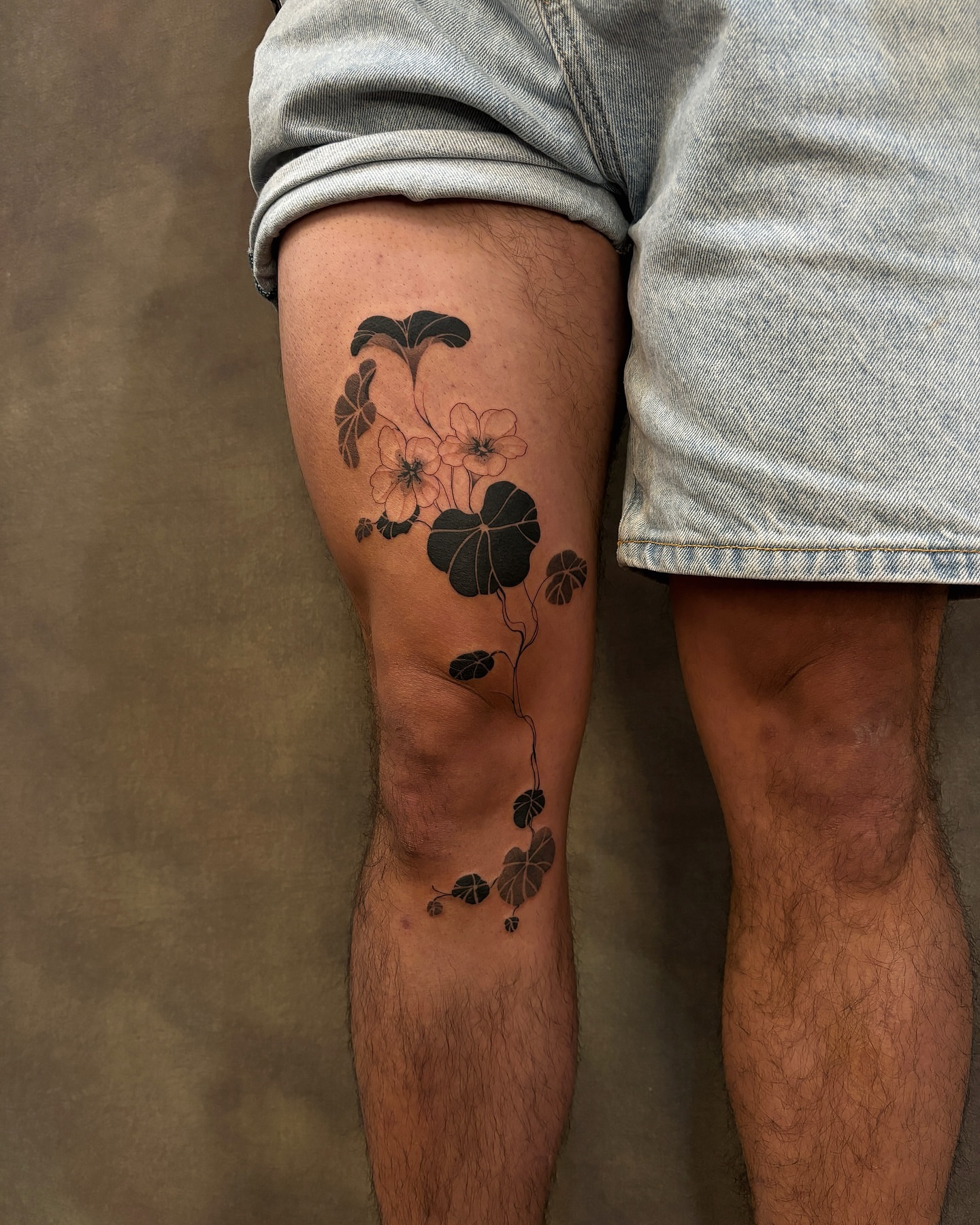 Flowers and leaves black and grey tattoo on the thigh by sago, Berkeley, California
