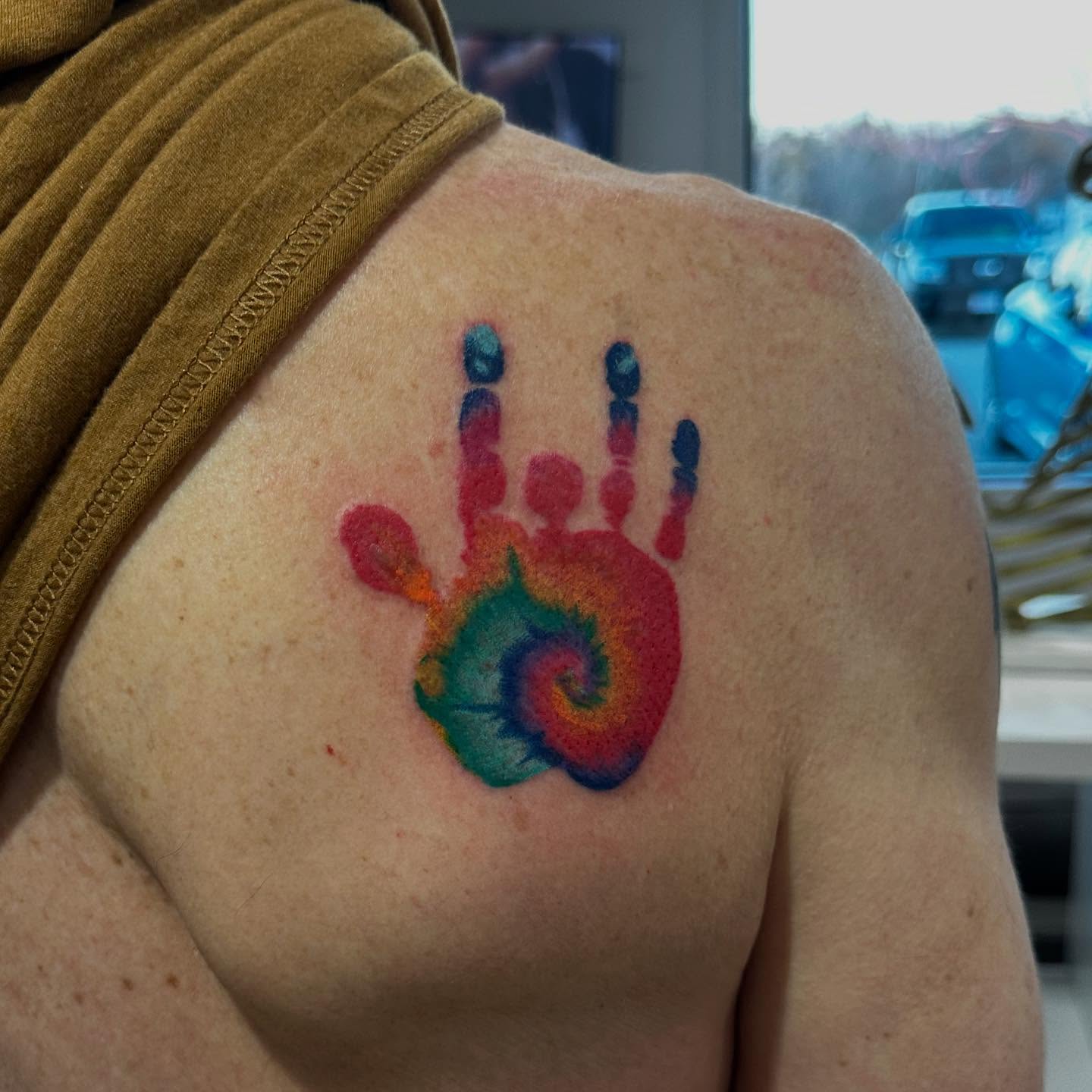 Rainbow handprint dotwork tattoo on the shoulder by Emma