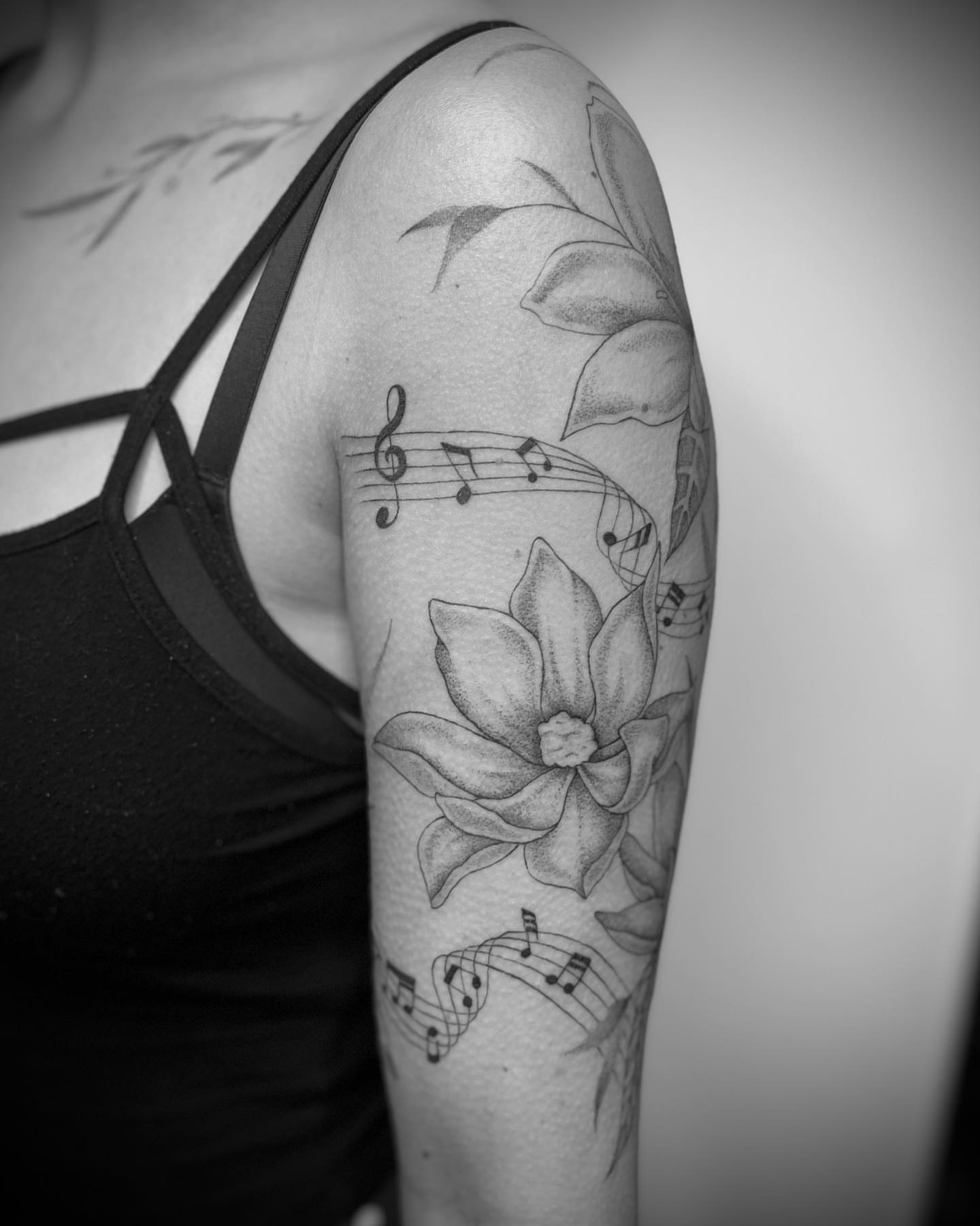 Lotus flower and music notes realism tattoo on the forearm by Andrea