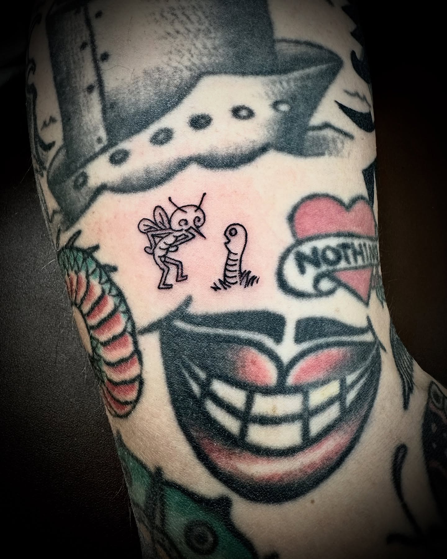 Smiling face with fly and worm American traditional tattoo on the forearm by Kristen
