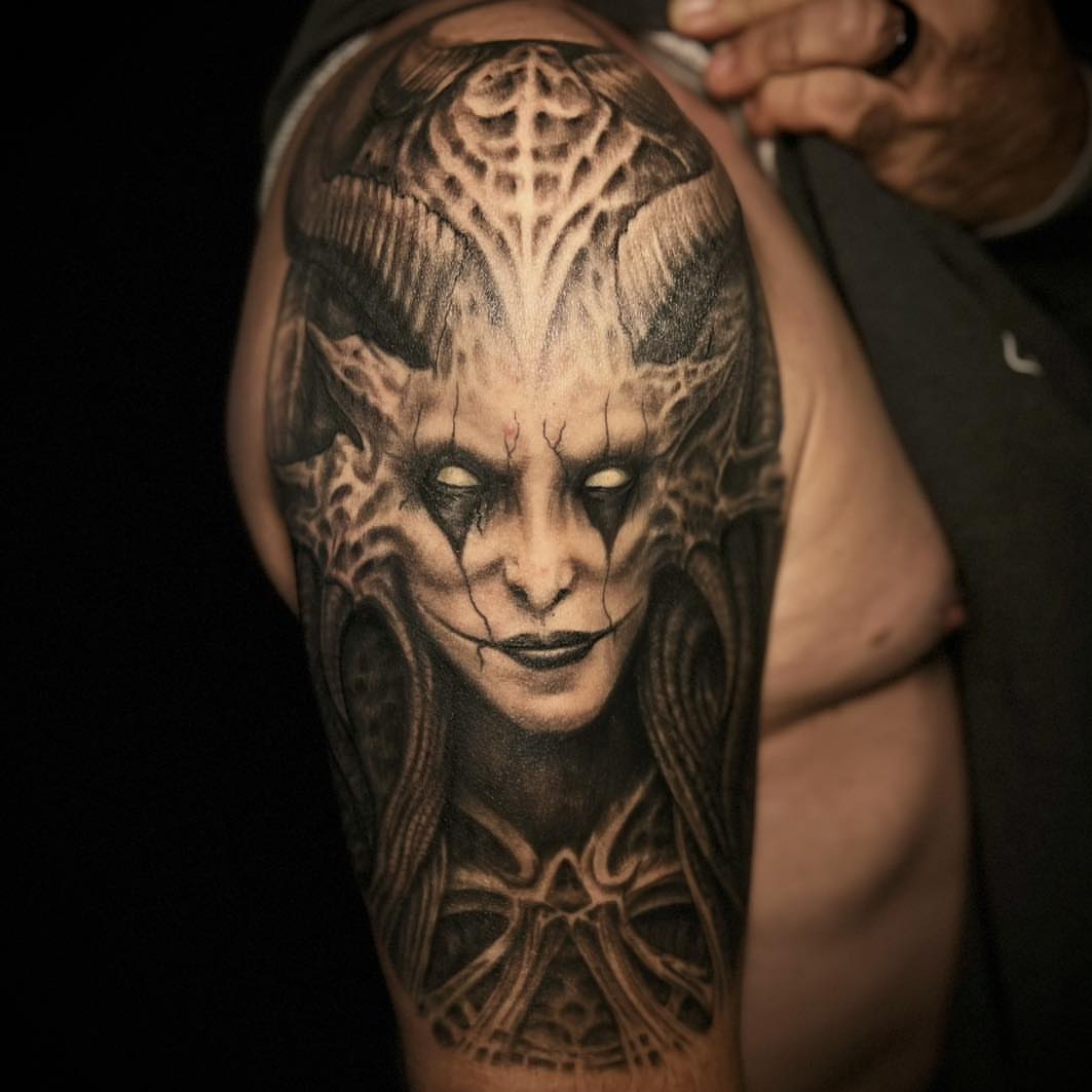 Demon face dark realism tattoo on the upper arm by James Reed Tattoo artist
