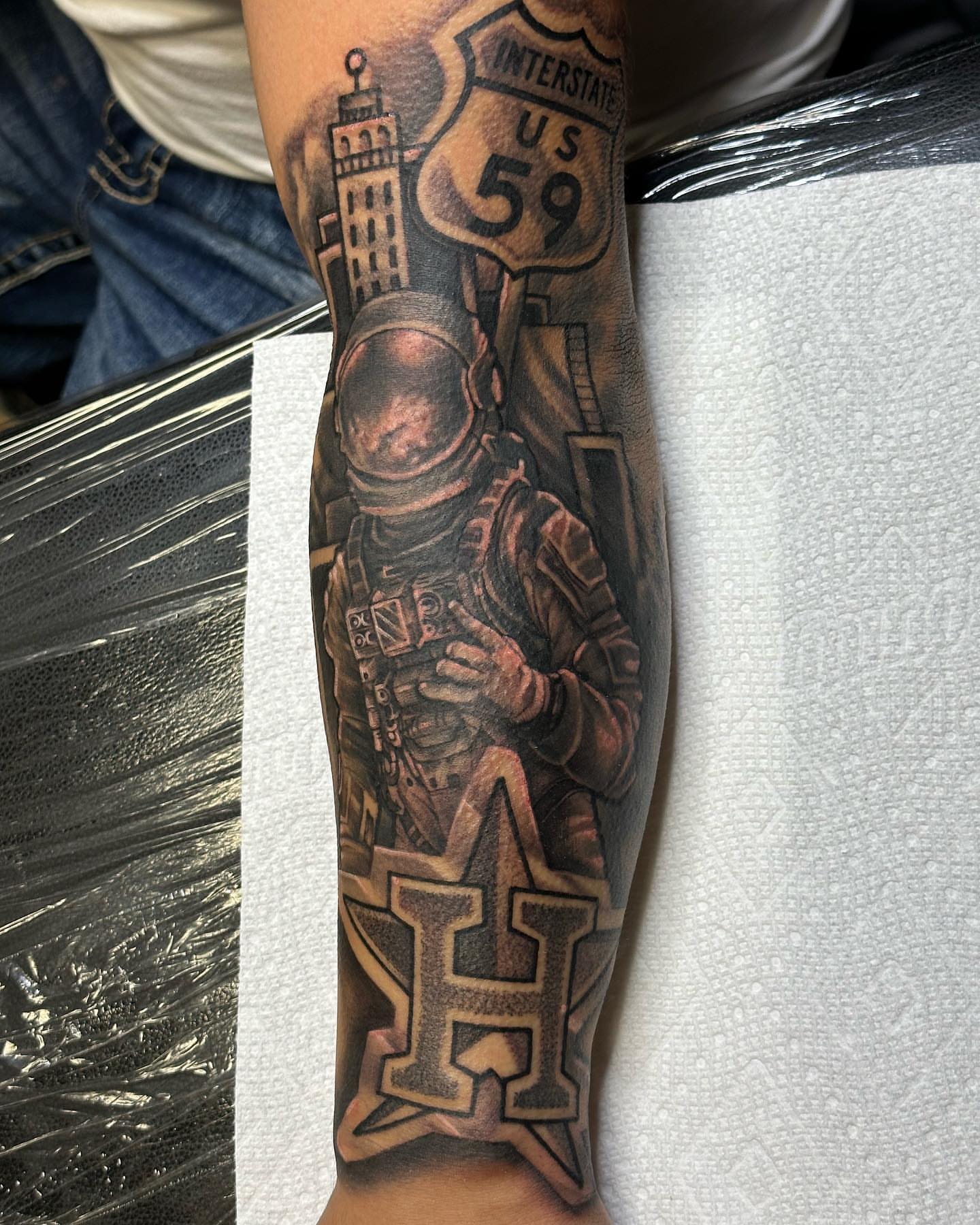 Astronaut with interstate sign realism tattoo on the forearm by Pablo Venegas