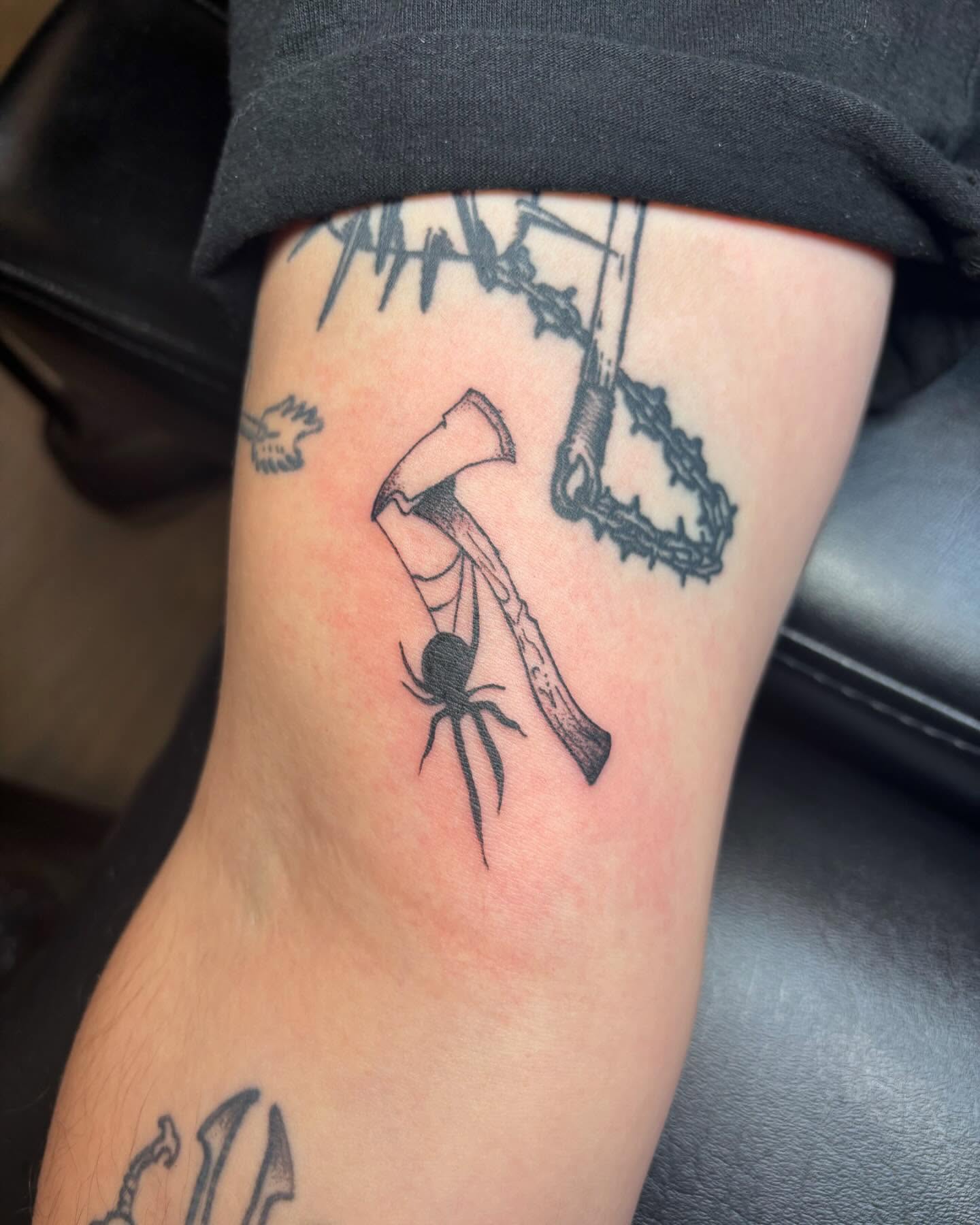 Axe and spider black and grey tattoo on the forearm by Bryan Black