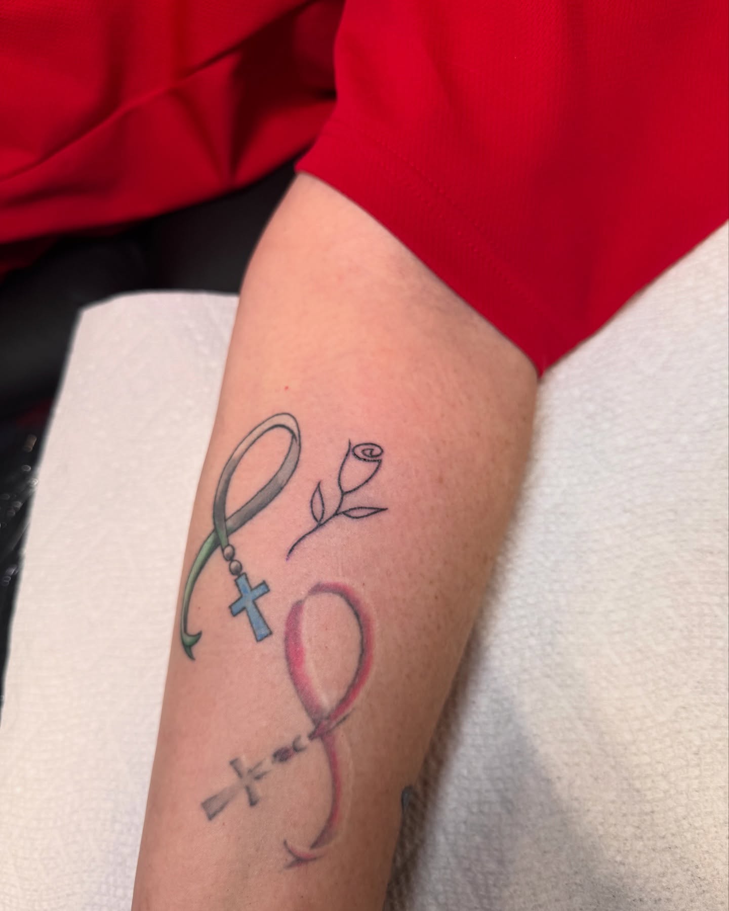 Infinity symbol with cross and rose new school tattoo on the forearm by Suda