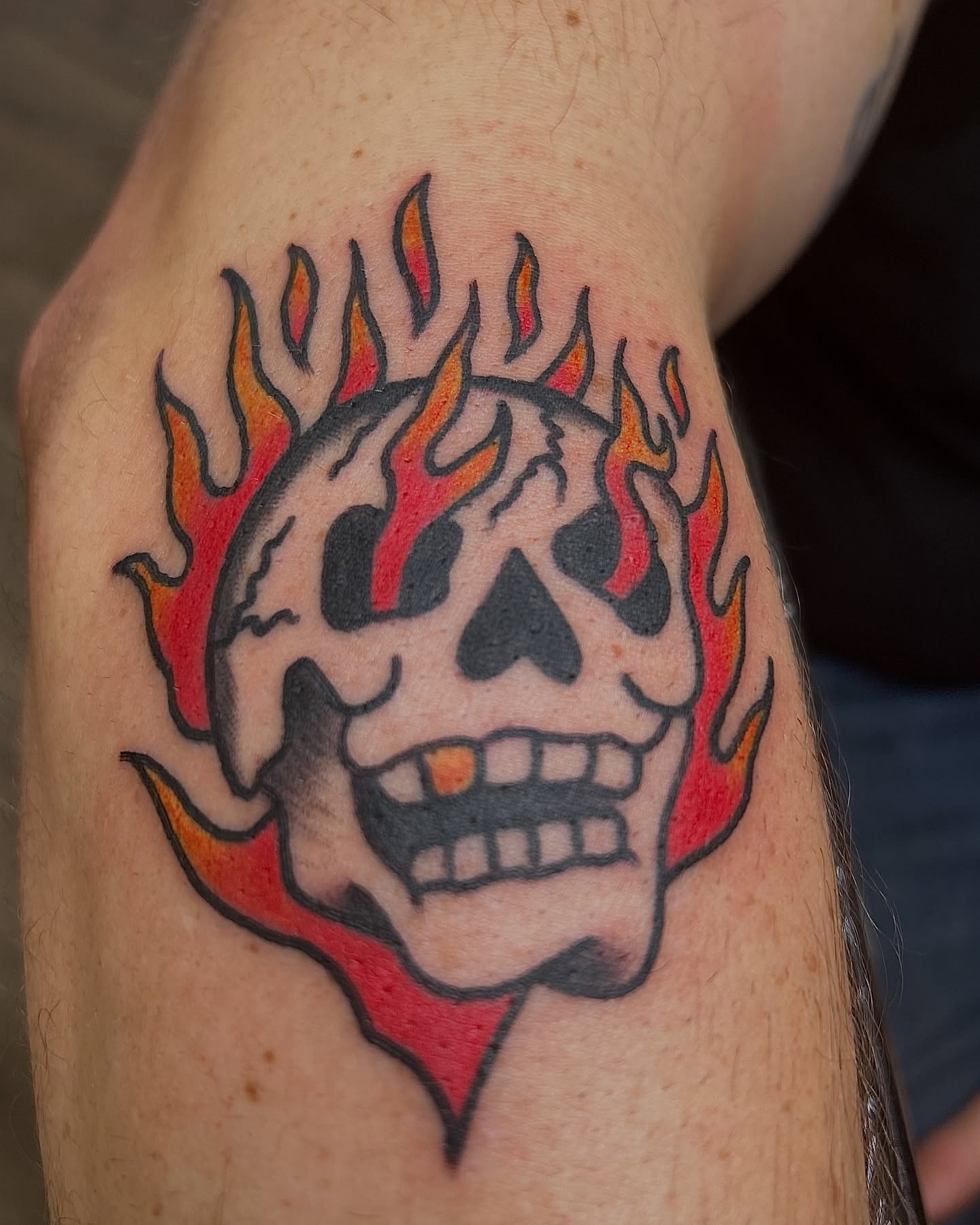 Flaming skull American traditional tattoo on the forearm by Alex Fannin