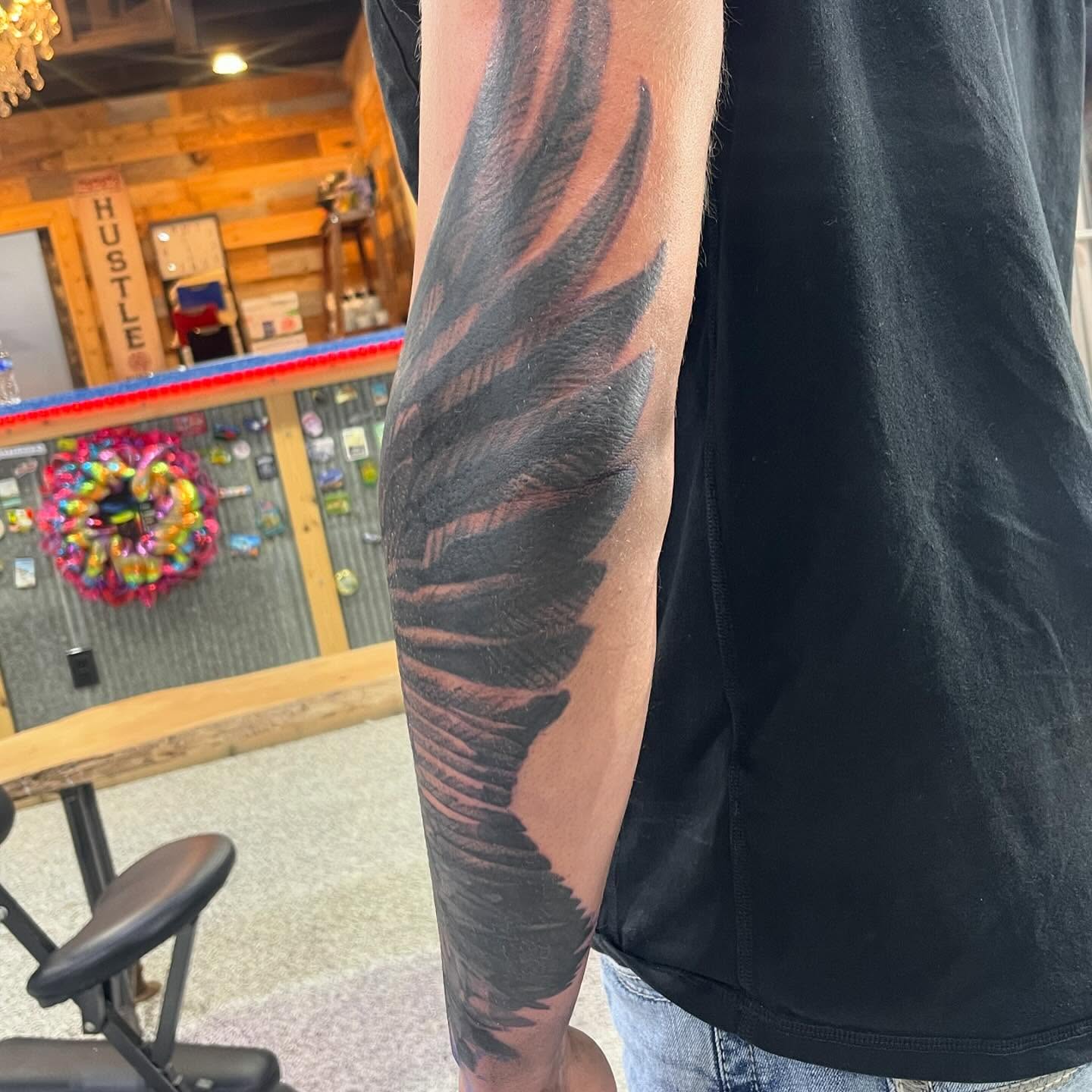 Feather black and grey tattoo on the forearm by Troy Butner
