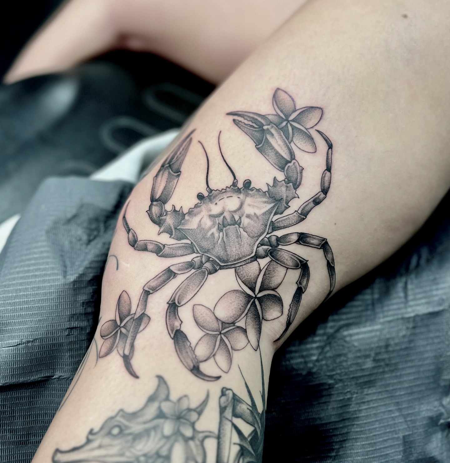 Crab with flowers realism tattoo on the forearm by Chelsea Speirs