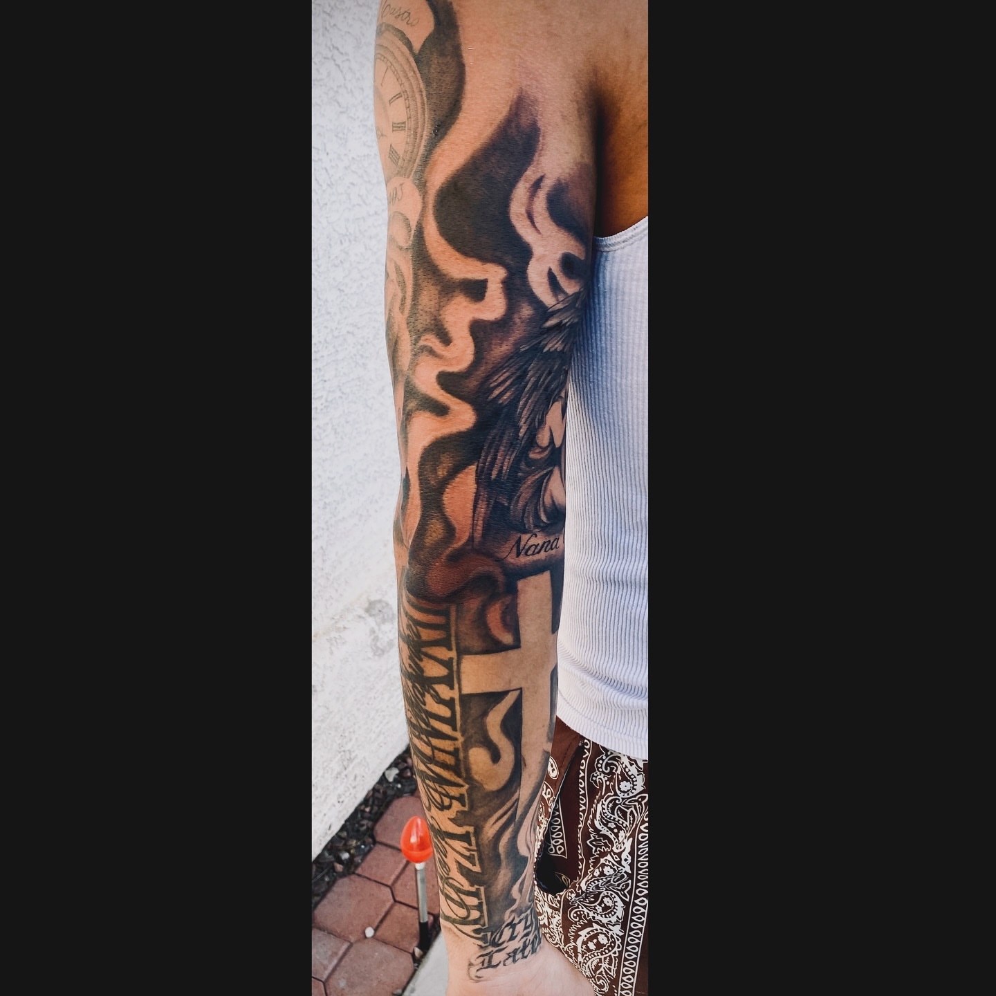 Flame and cross black and grey tattoo on the forearm by Nessa, Las Vegas, Nevada