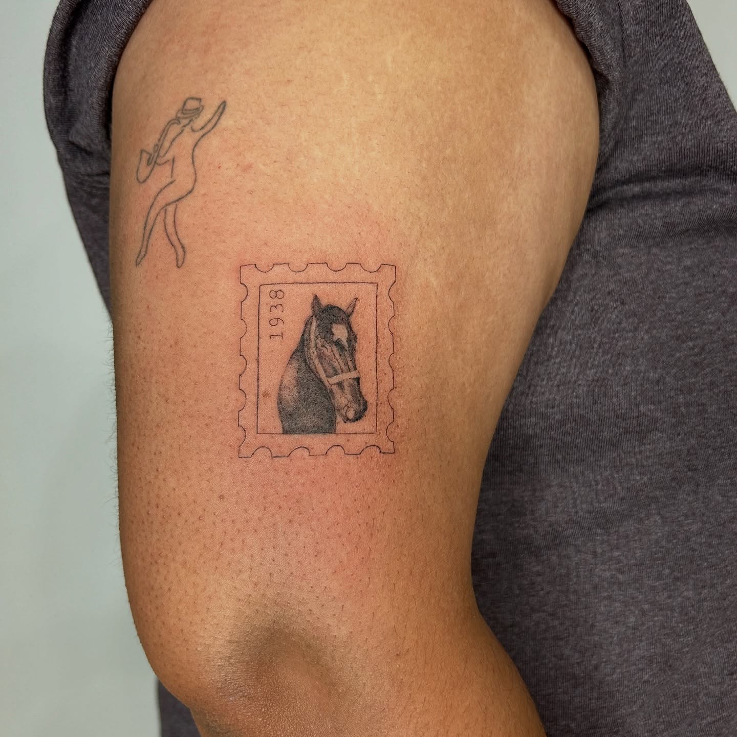 Horse stamp black and grey tattoo on the upper arm by bre
