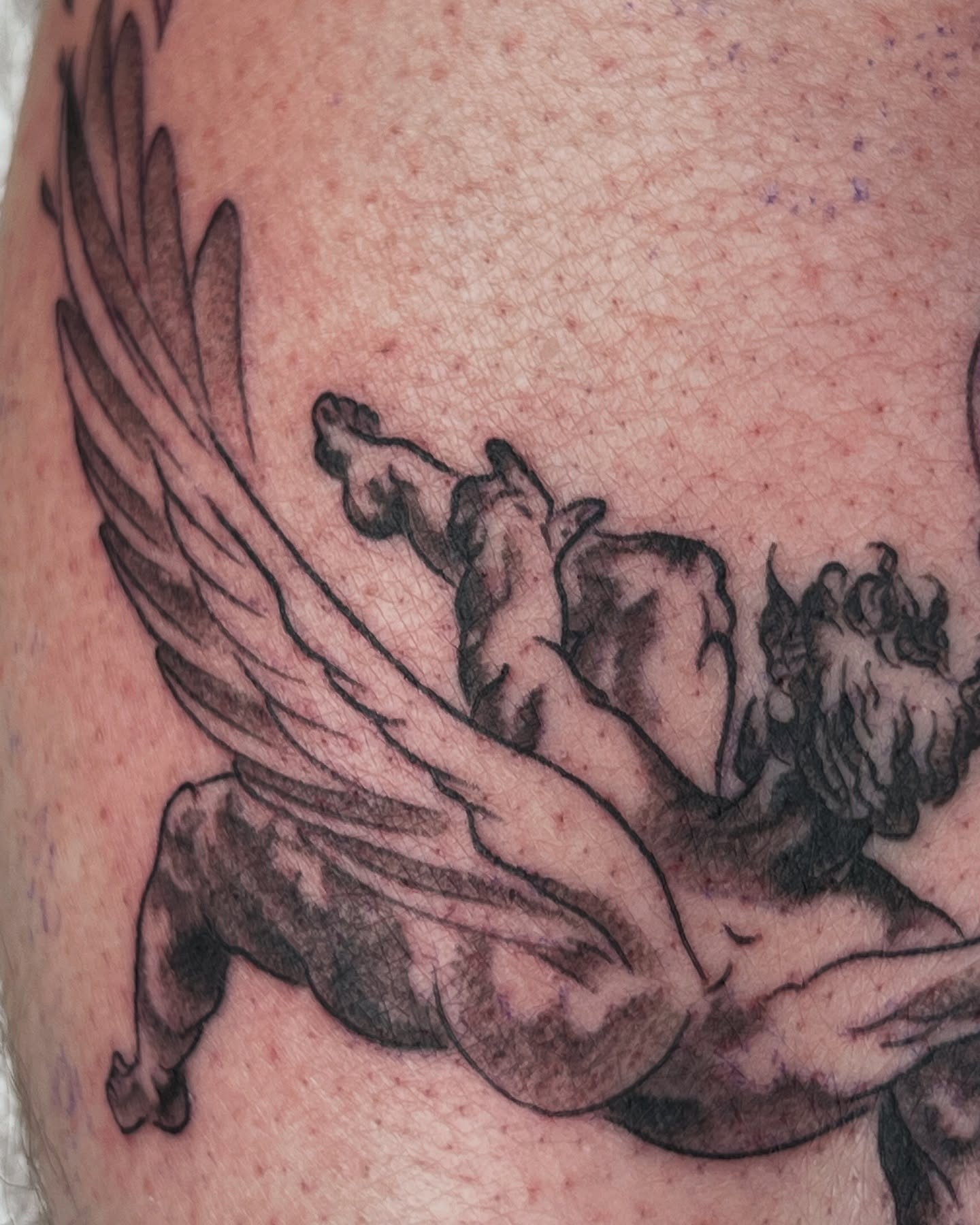 Winged creature black and grey tattoo on the upper arm by Cory Miller