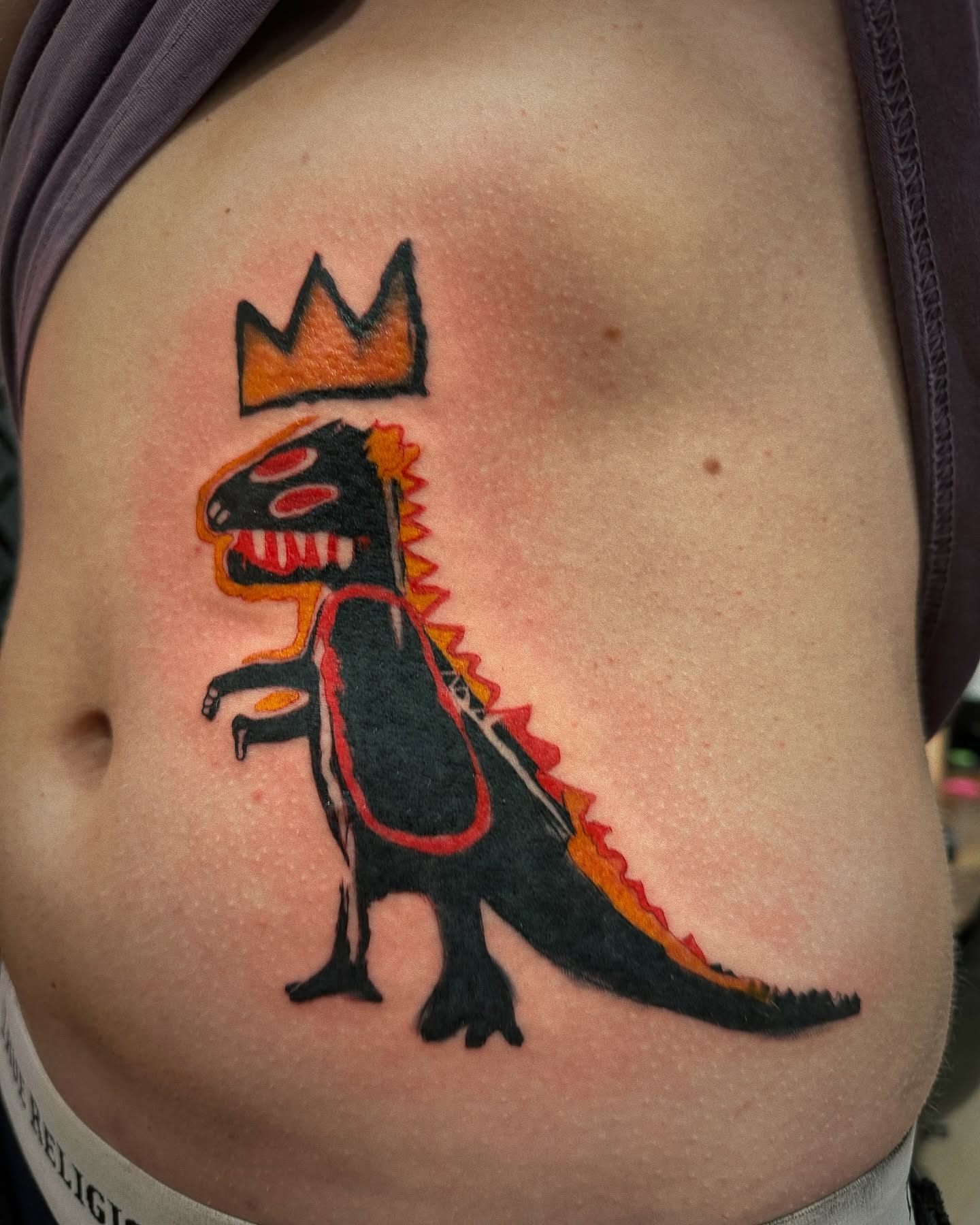 Dinosaur with crown American traditional tattoo on the ribs by 🌙Jose Maldonado🌙