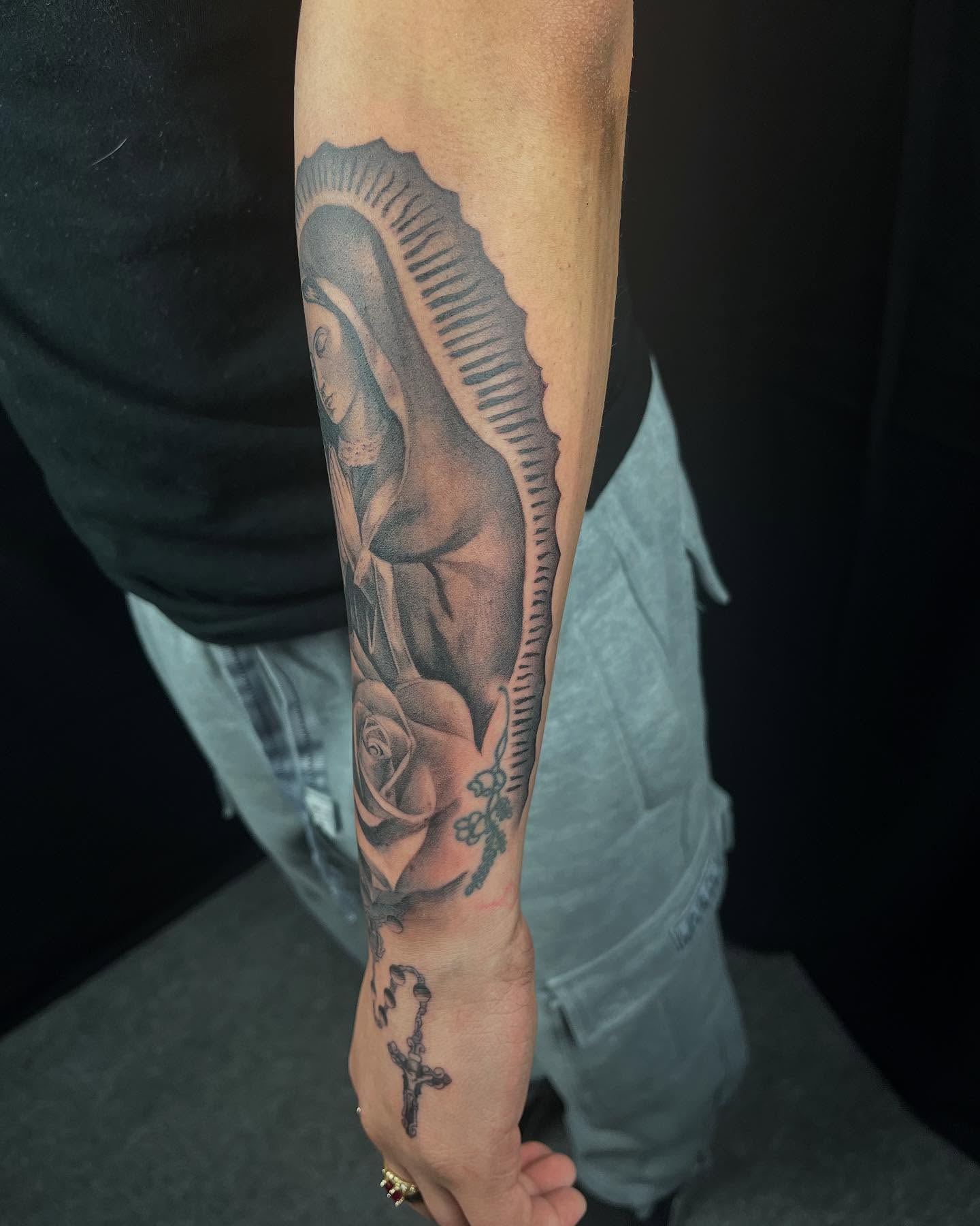 Religious figure with rose realism tattoo on the forearm by Denver Tattoo Artist