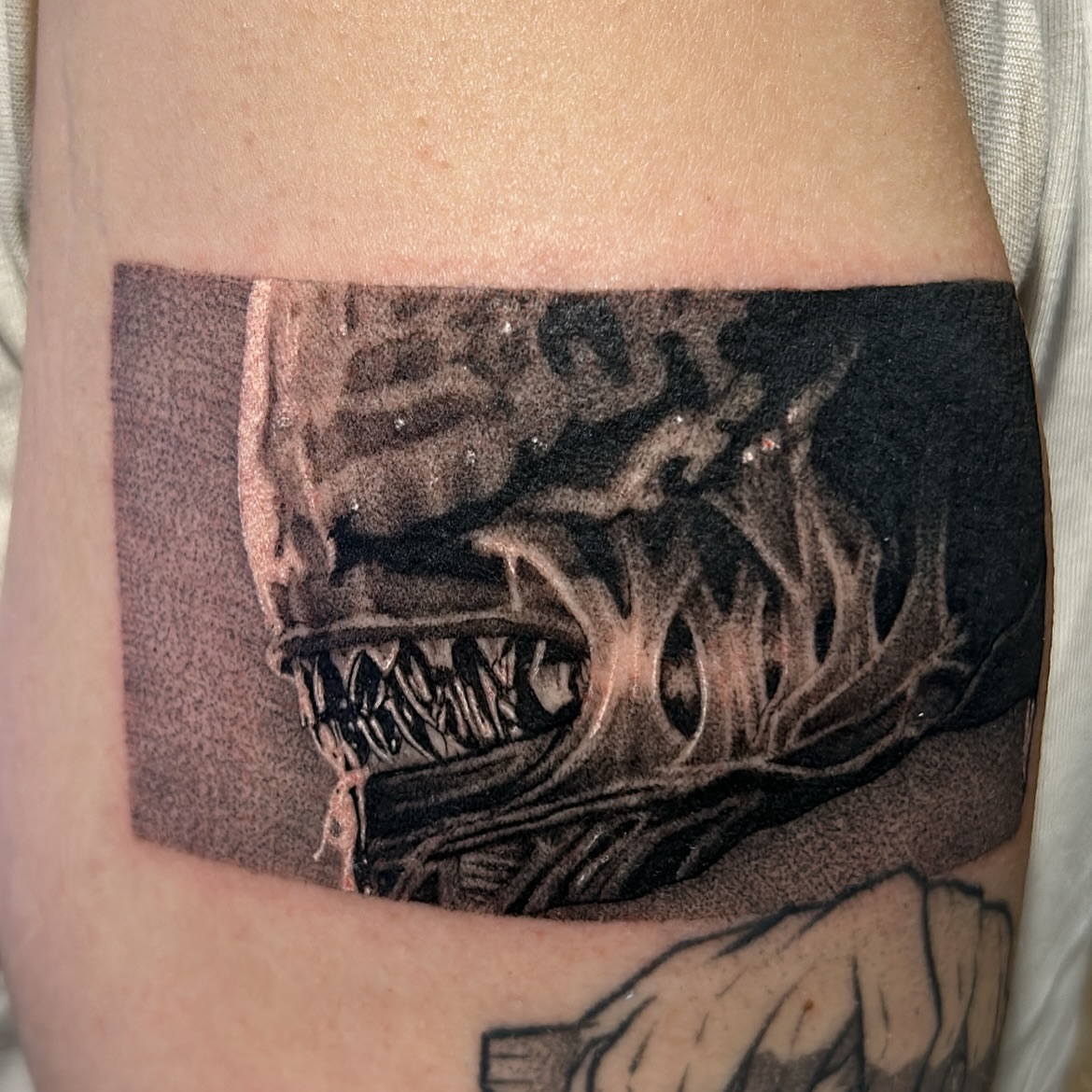 Alien creature dark realism tattoo on the forearm by Roman Butryy