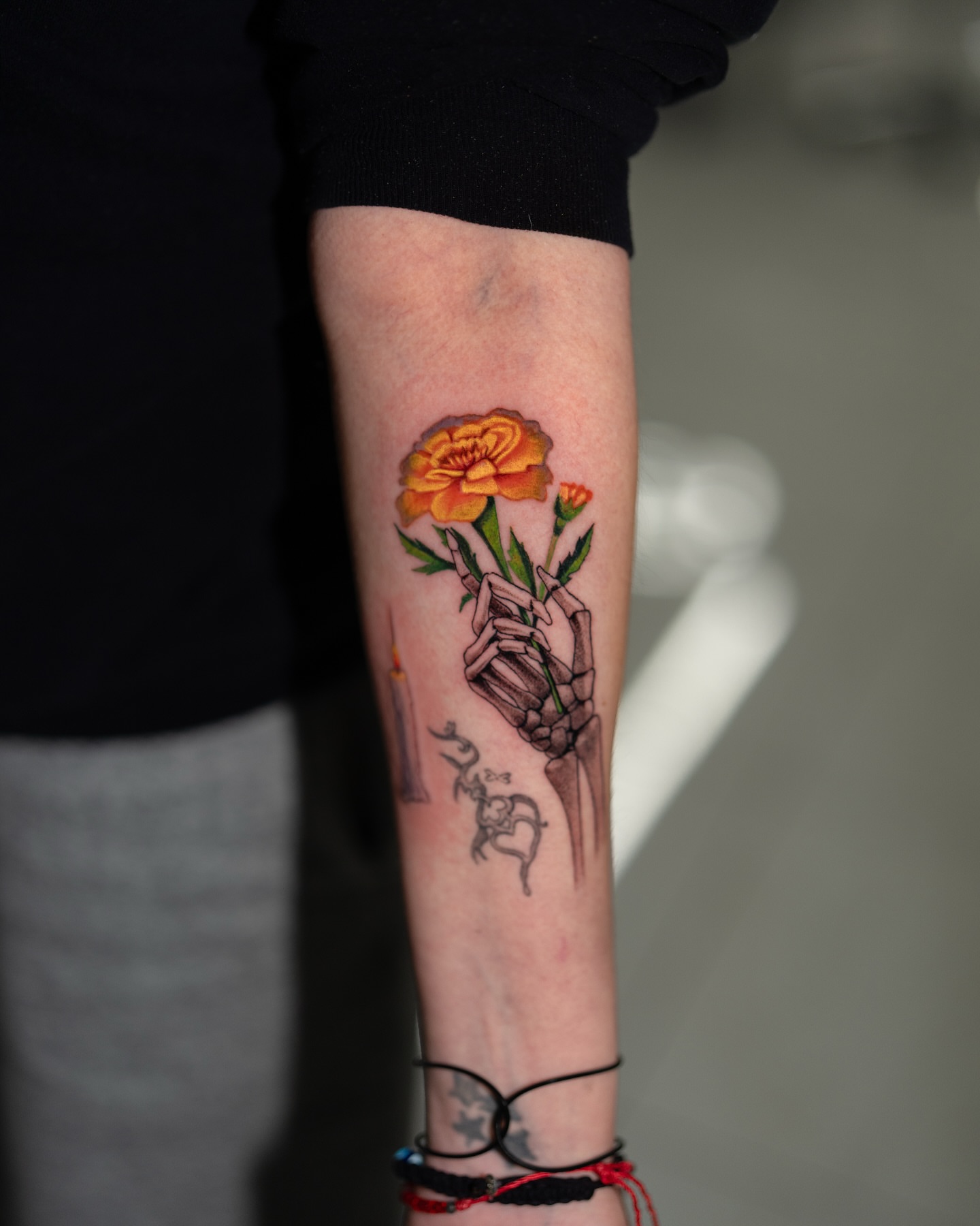Marigold and skeleton hand realism tattoo on the forearm by Joey Hella Tattoo Artist