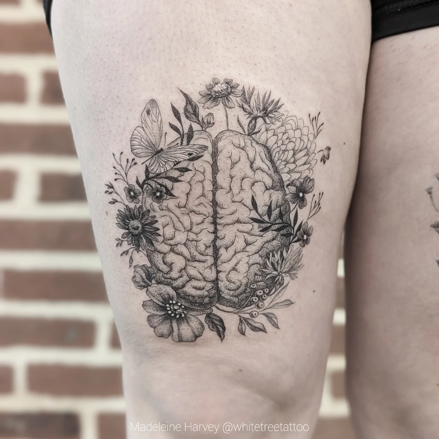 Brain with floral elements realism tattoo on the thigh by Maddie