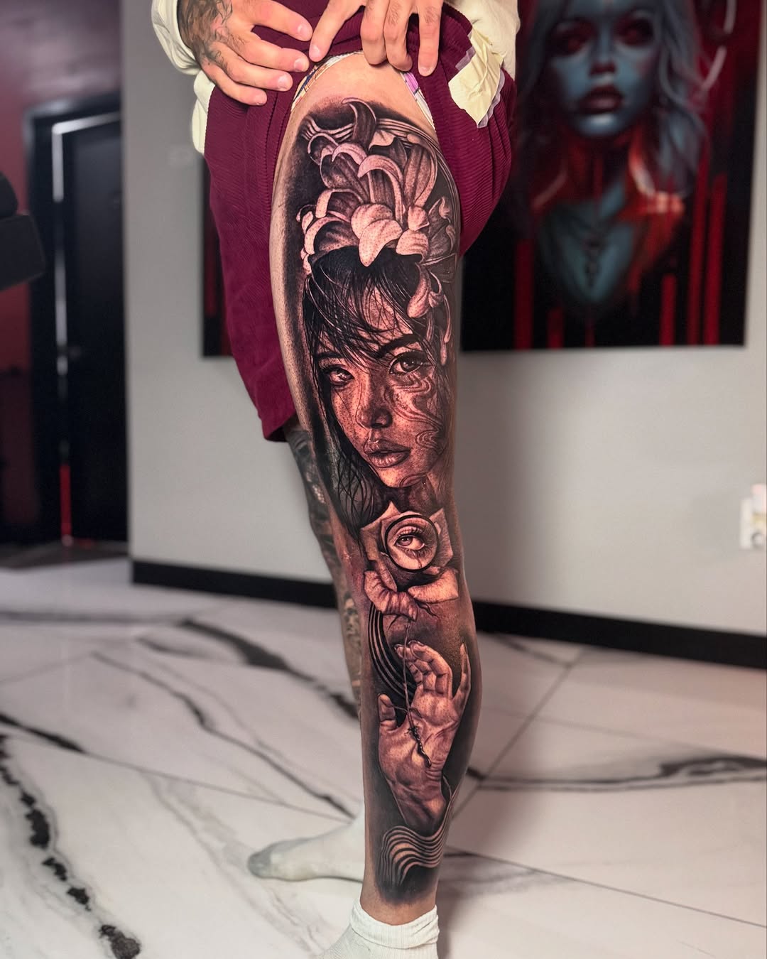 Woman's face with flowers and hand surrealism tattoo on the leg by Mia