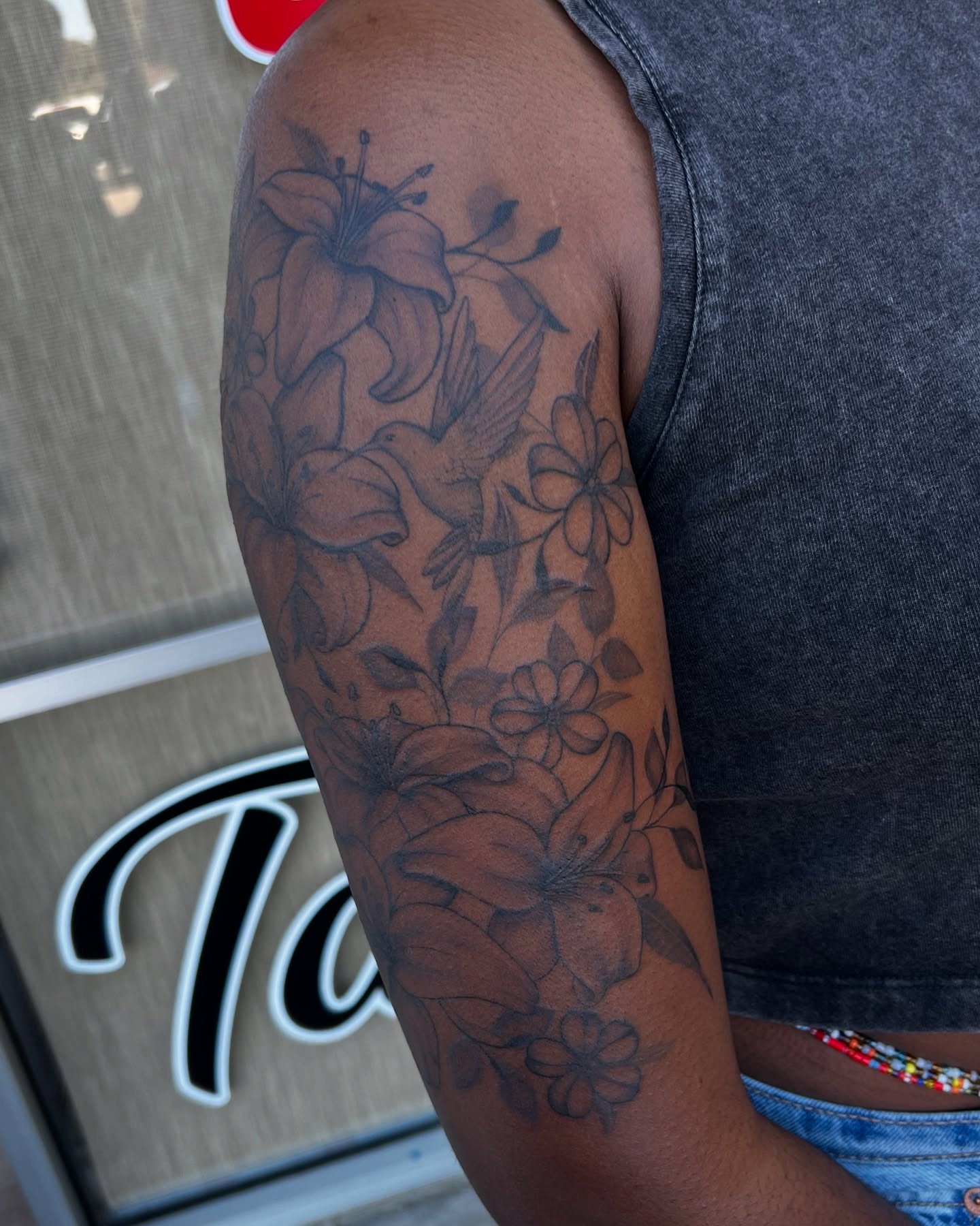 Lilies and flowers black and grey tattoo on the upper arm by tatman cris 🥀 dfw tattoo artist