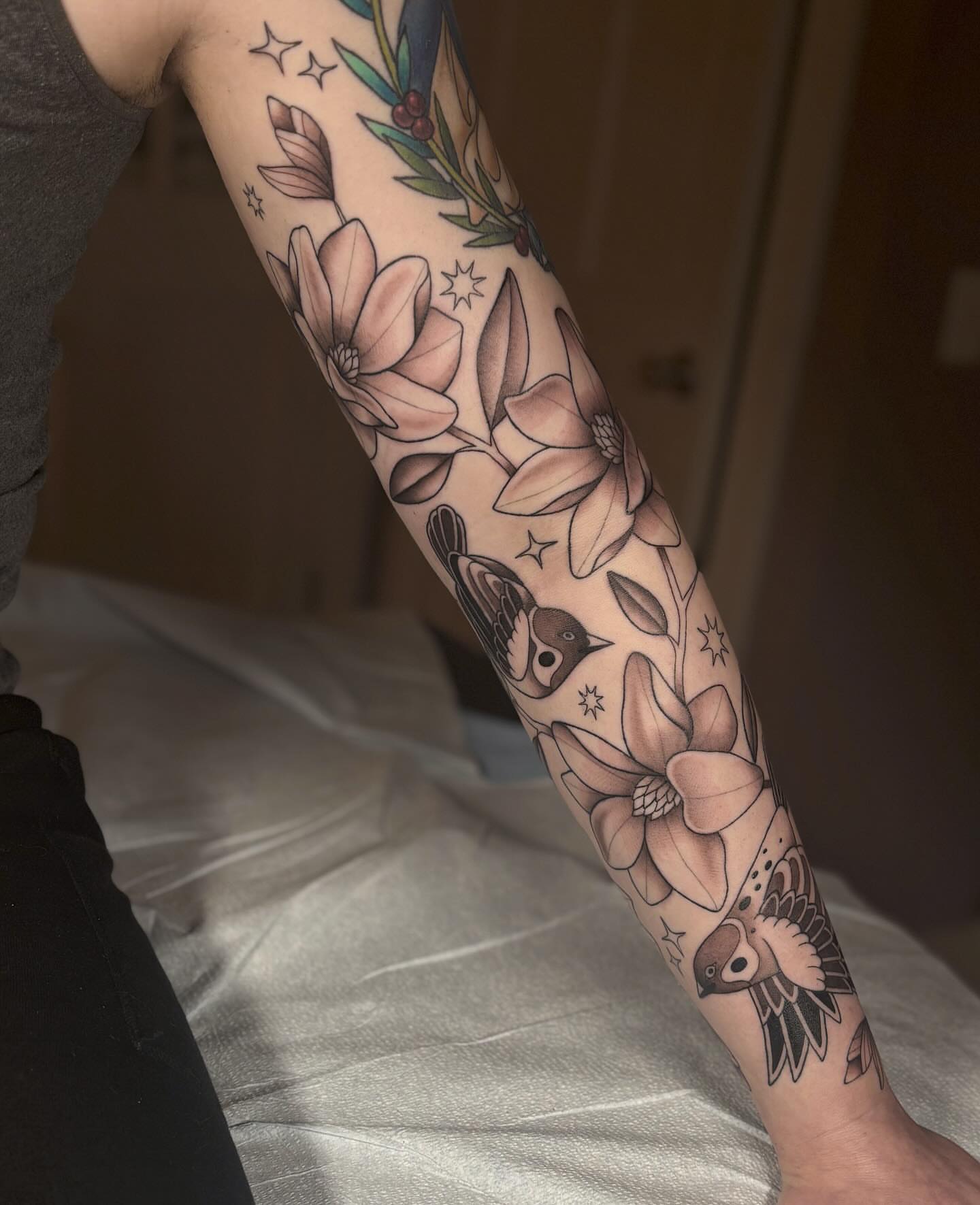 Magnolia flowers and birds neo-traditional tattoo on the forearm by Anna Sage