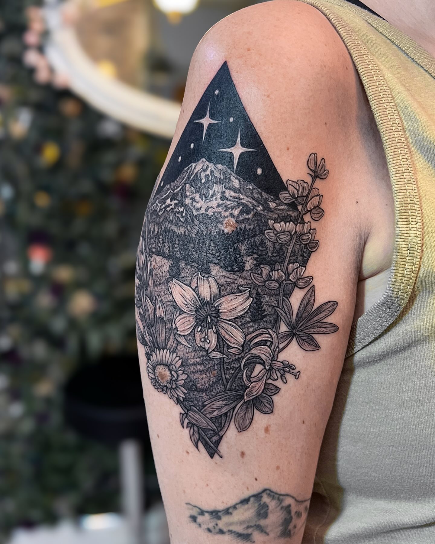 Mountain and flowers geometric tattoo on the upper arm by 𝗝𝗲𝘀𝘀𝗶𝗲 𝗩𝗶𝗼𝗹𝗲𝘁