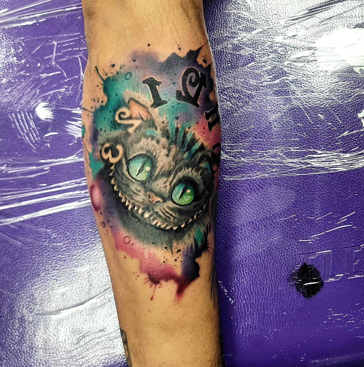Cheshire cat watercolor tattoo on the forearm by Jentrey McCausland
