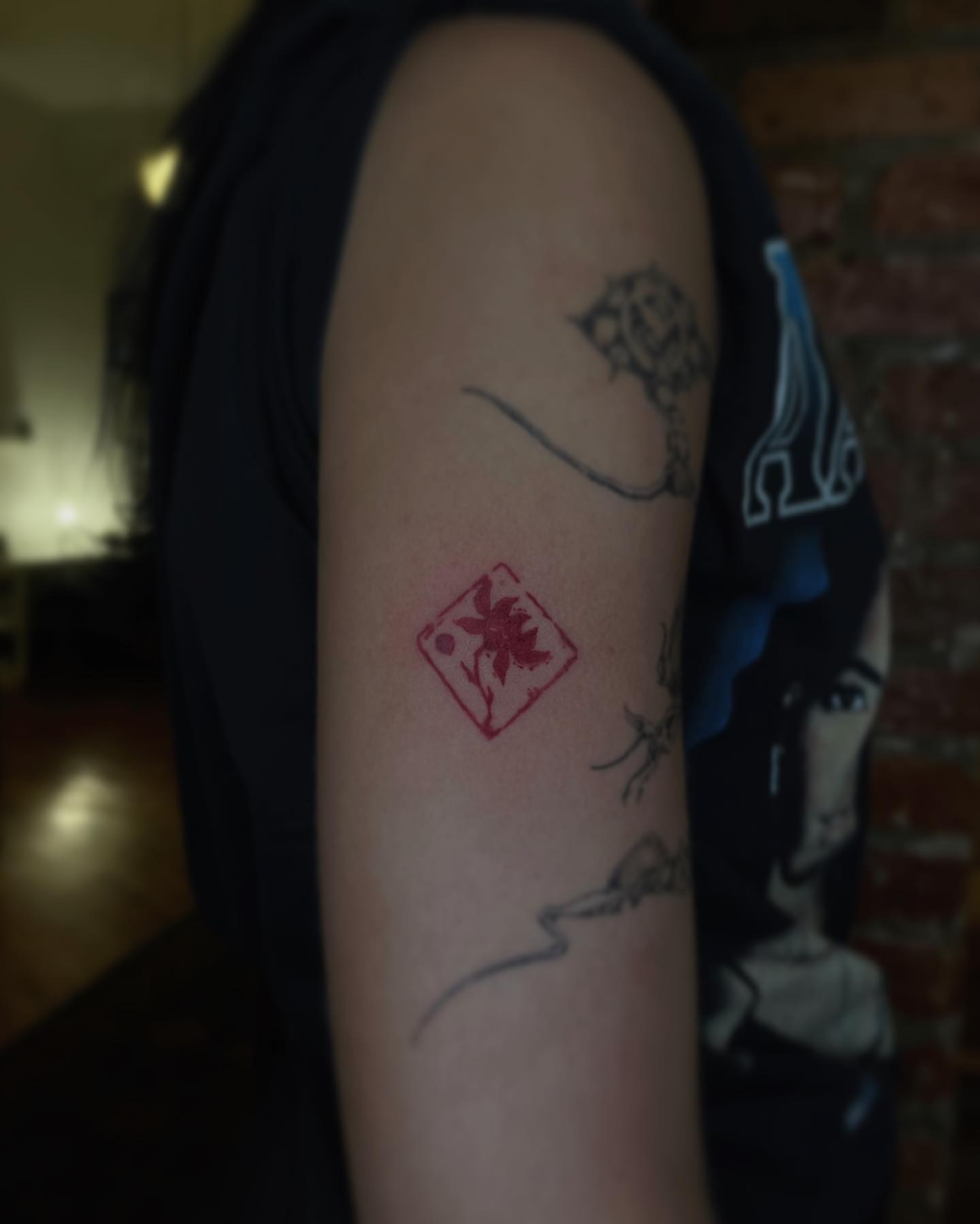 Red stamp geometric tattoo on the forearm by San Kang