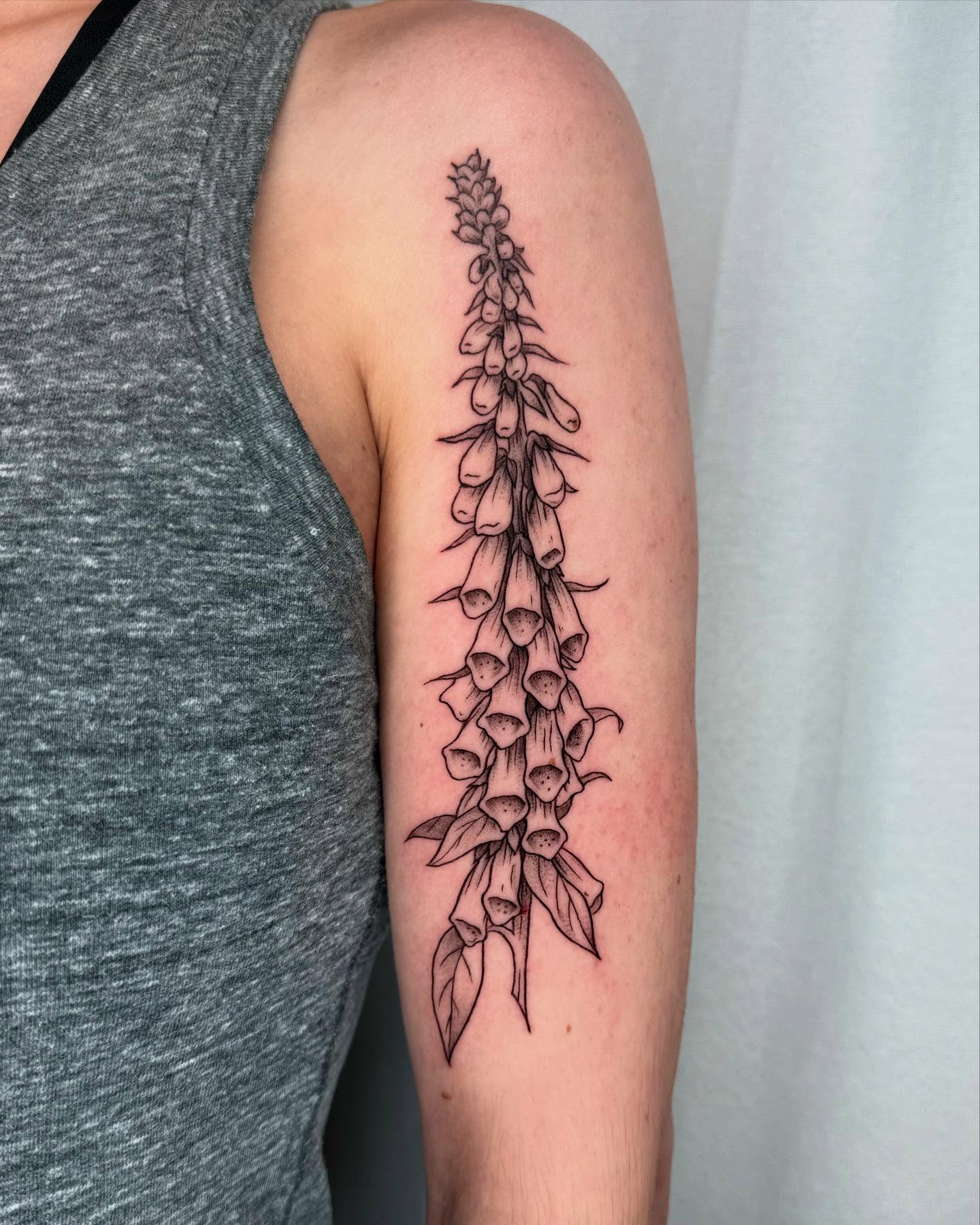 Foxglove plant black and grey tattoo on the forearm by Cooper