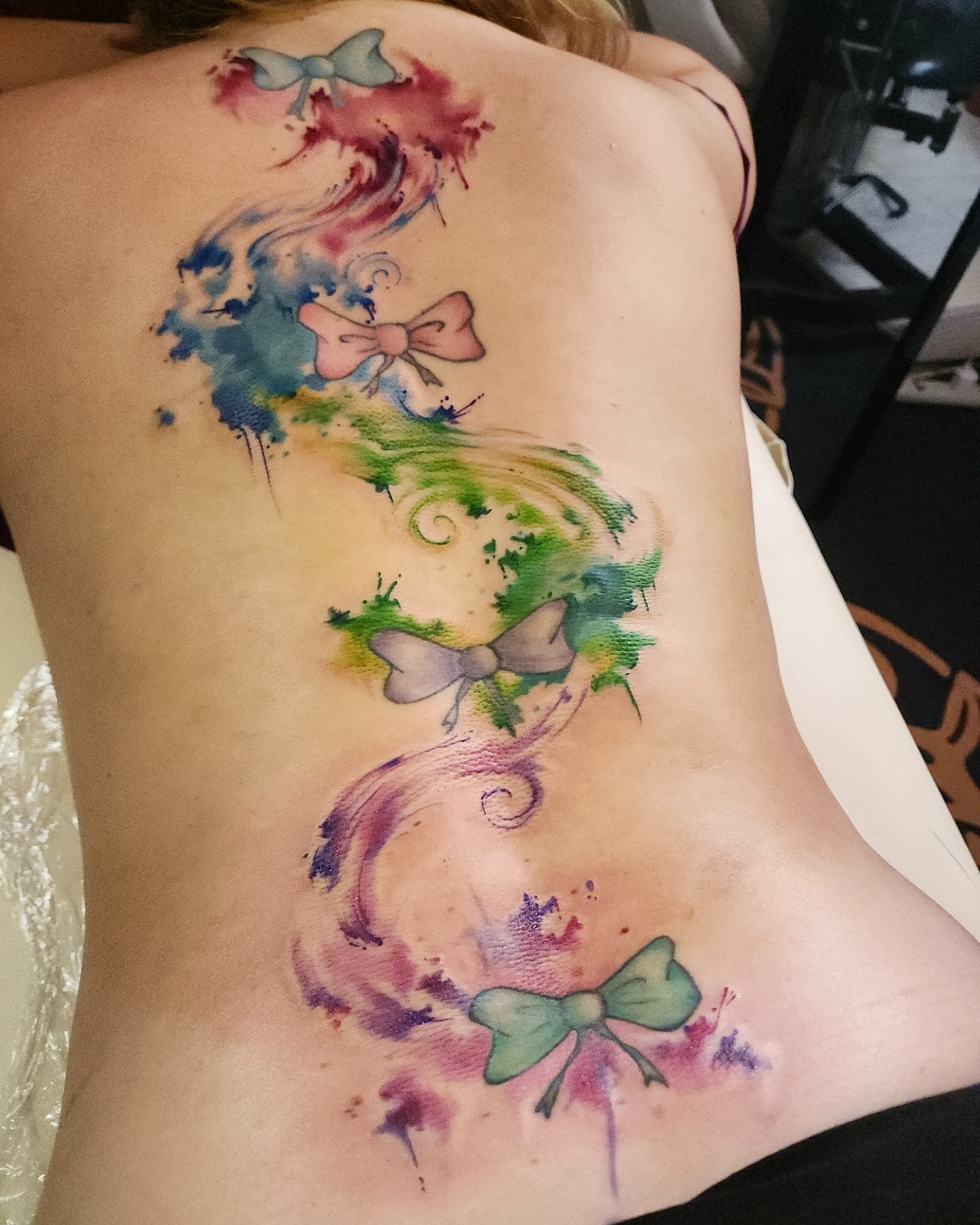 Watercolor bow watercolor tattoo on the back by ✨Vii Duquette✨