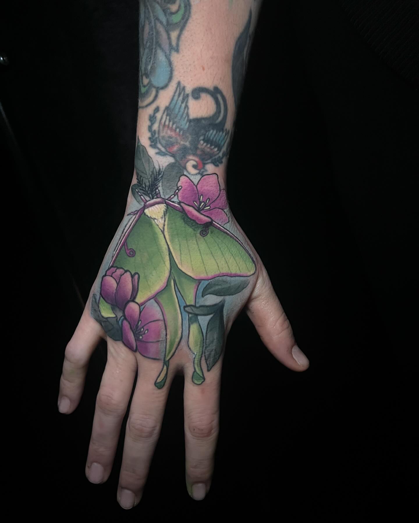Luna moth and flowers realism tattoo on the hand by Emily Walker