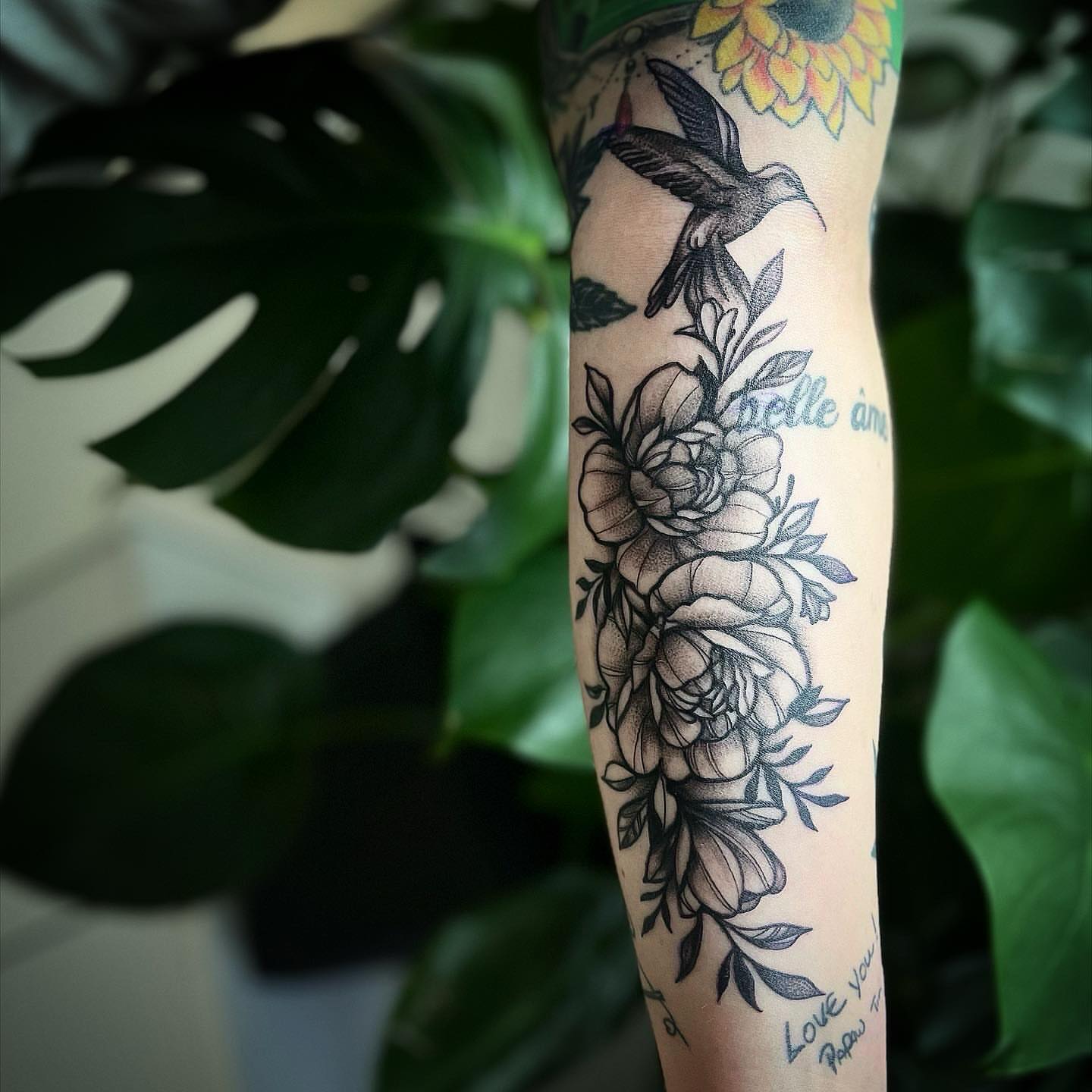 Floral bouquet with hummingbird black and grey tattoo on the forearm by π΅πππππ