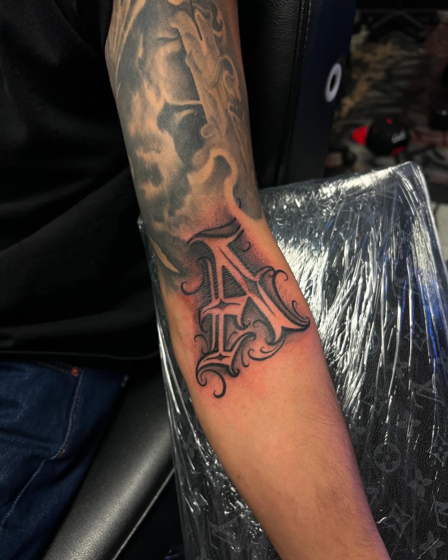 Lettering black and grey tattoo on the forearm by Smuk One