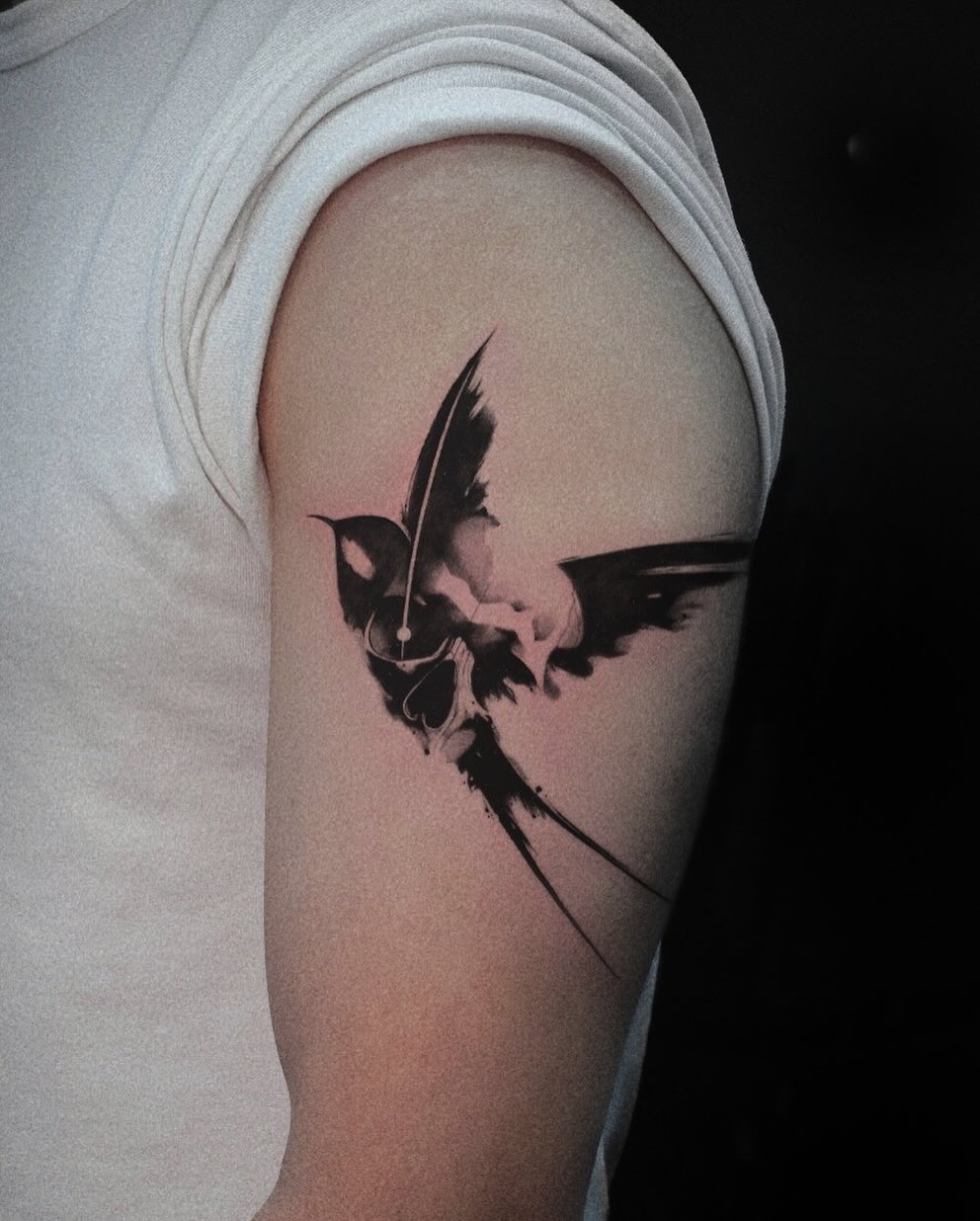 Bird black and grey tattoo on the upper arm by 𝑴𝒆𝒍𝒐