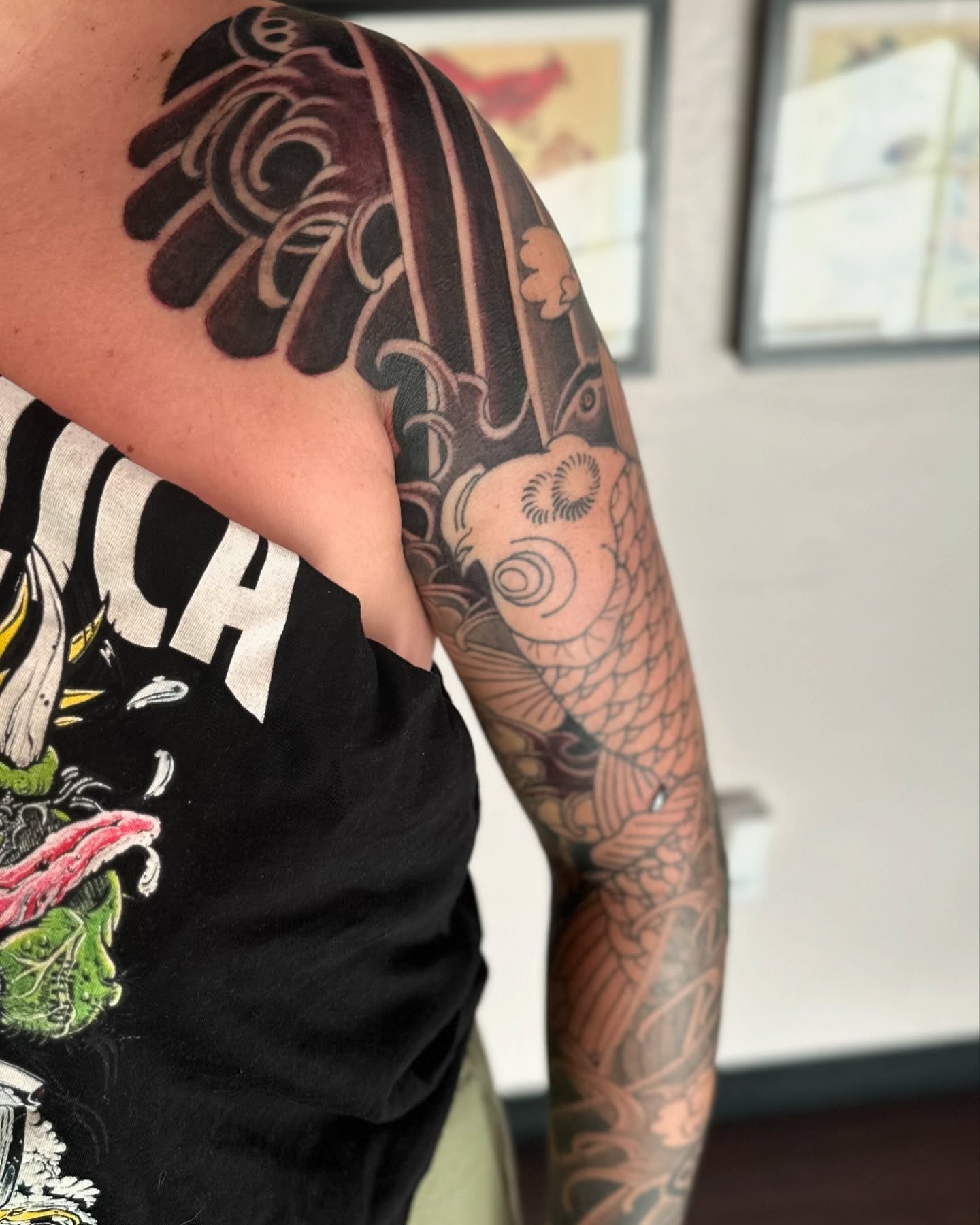Koi fish and floral japanese irezumi tattoo on the upper arm by Kenny Waizumi ๐