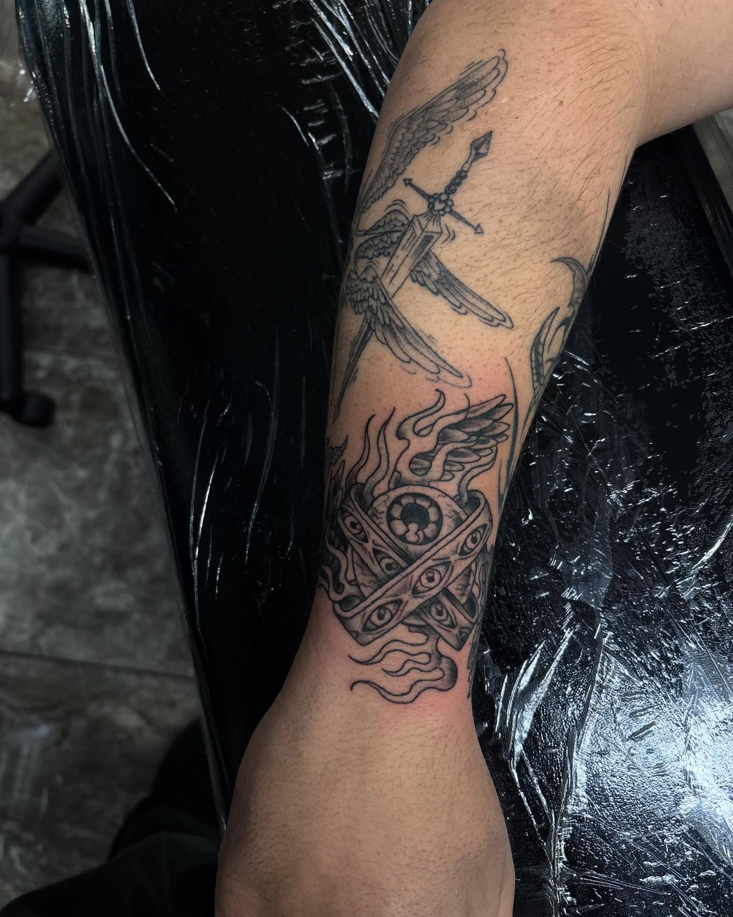 Eye and flame black and grey tattoo on the forearm by Ares Rhodes