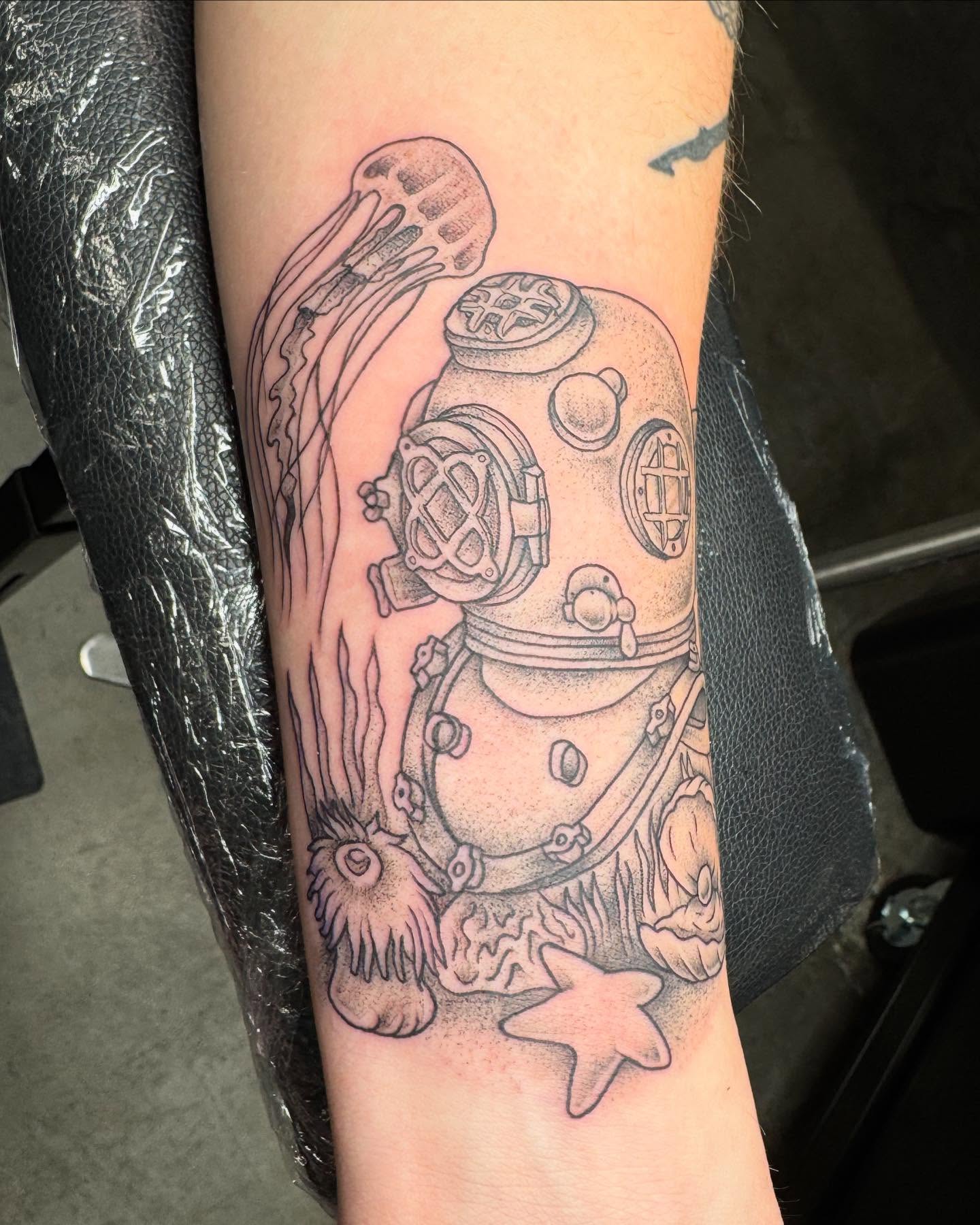 Diving helmet black and grey tattoo on the forearm by Cory Perry-Servellon