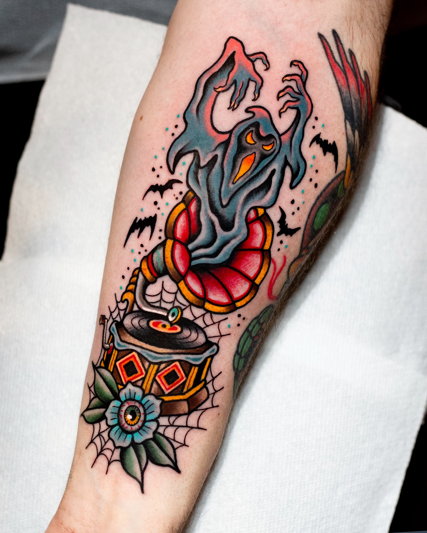 Ghostly figure with record player American traditional tattoo on the forearm by Miguel Comin