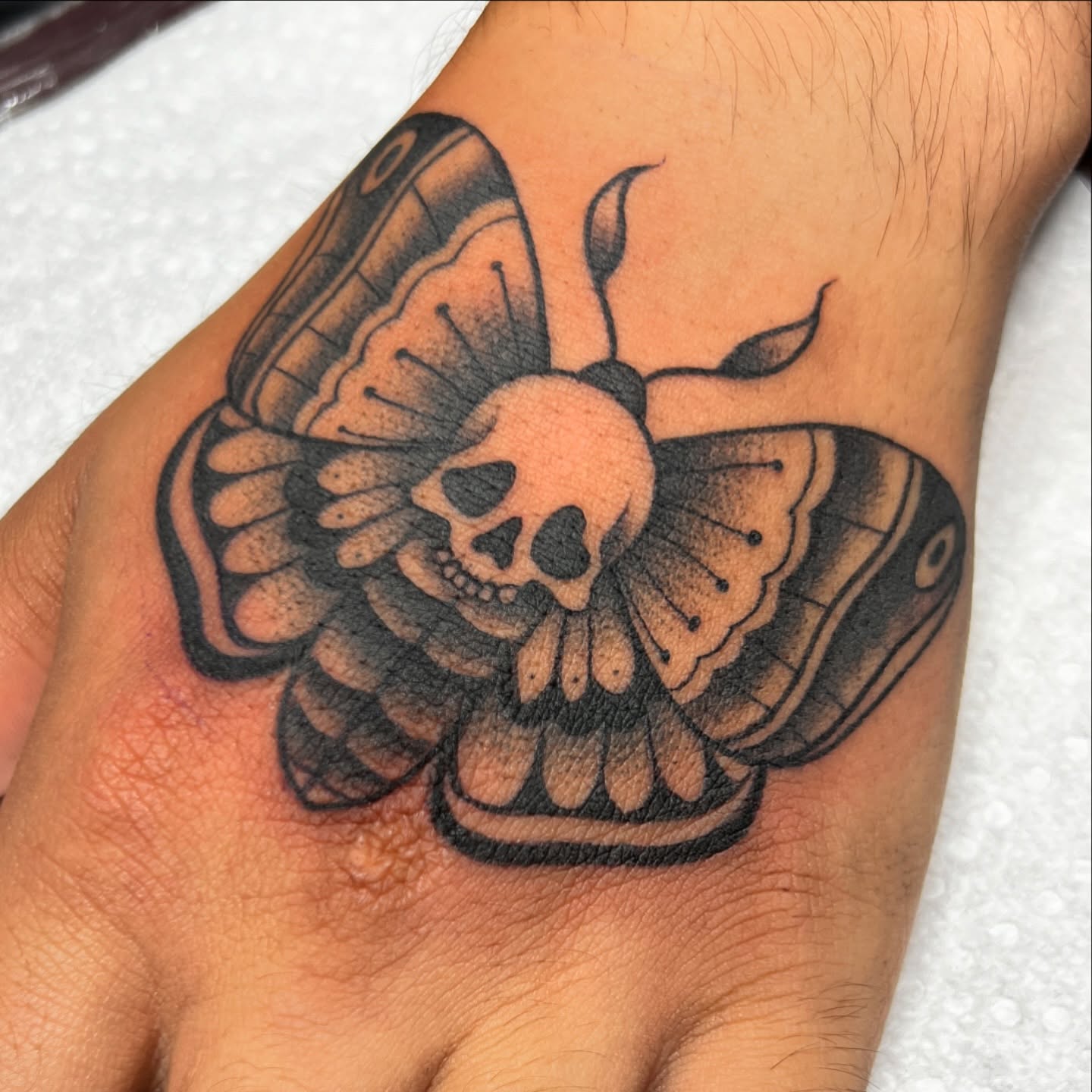 Skull moth American traditional tattoo on the hand by Nick Ochoa