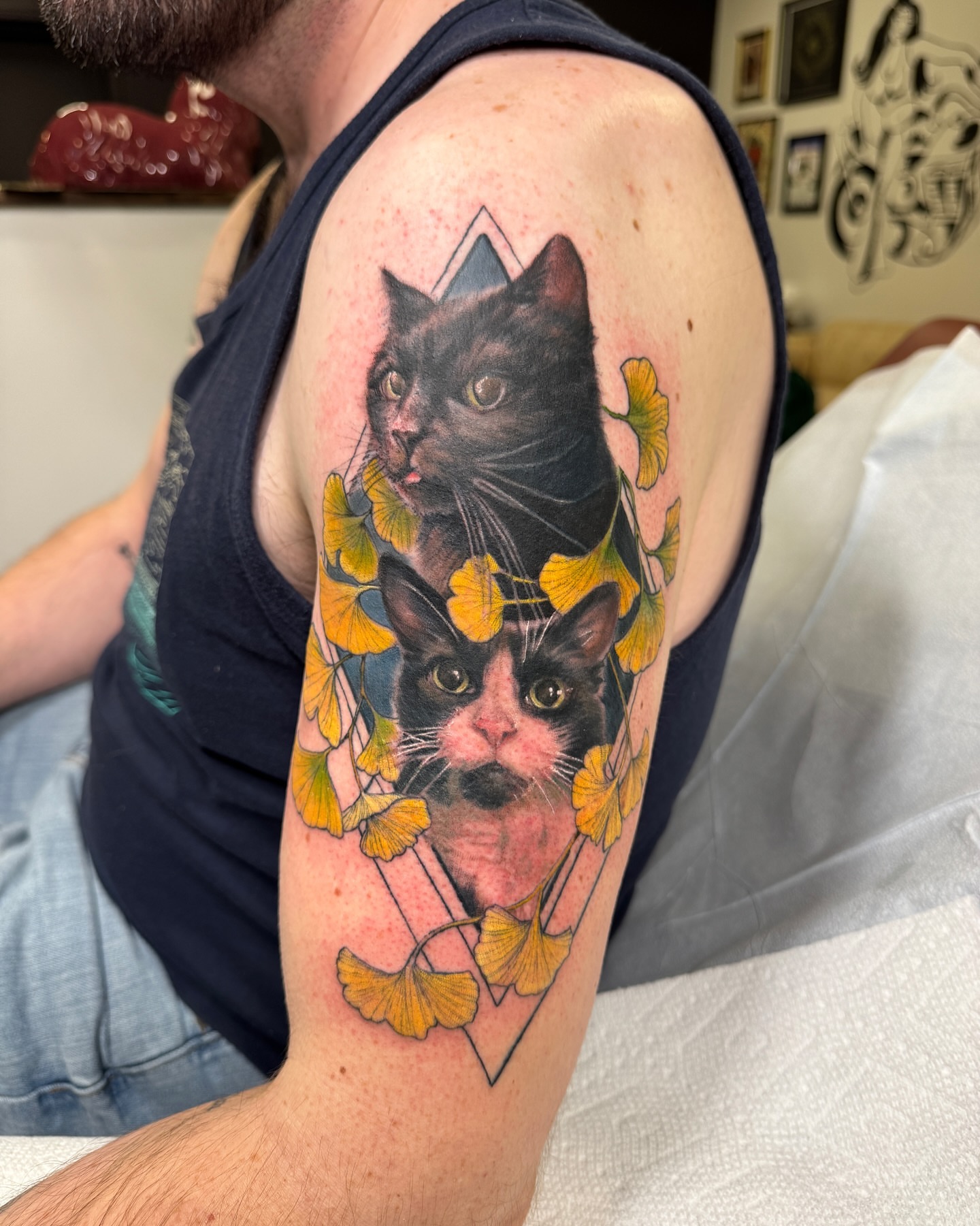 Cats and ginkgo leaves realism tattoo on the upper arm by Amber Miracle