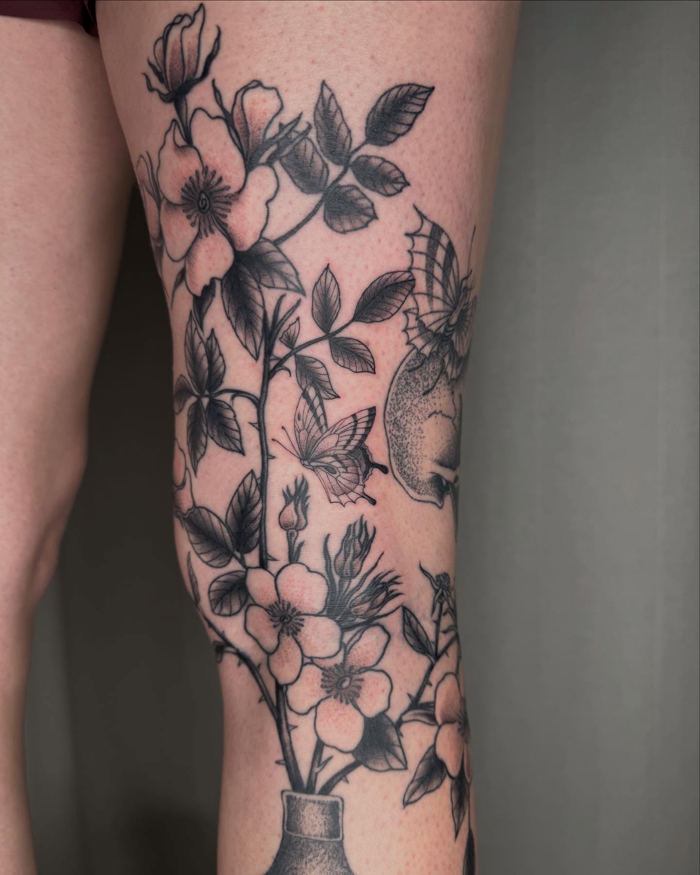 Flowers and butterflies black and grey tattoo on the forearm by Finley Jordan