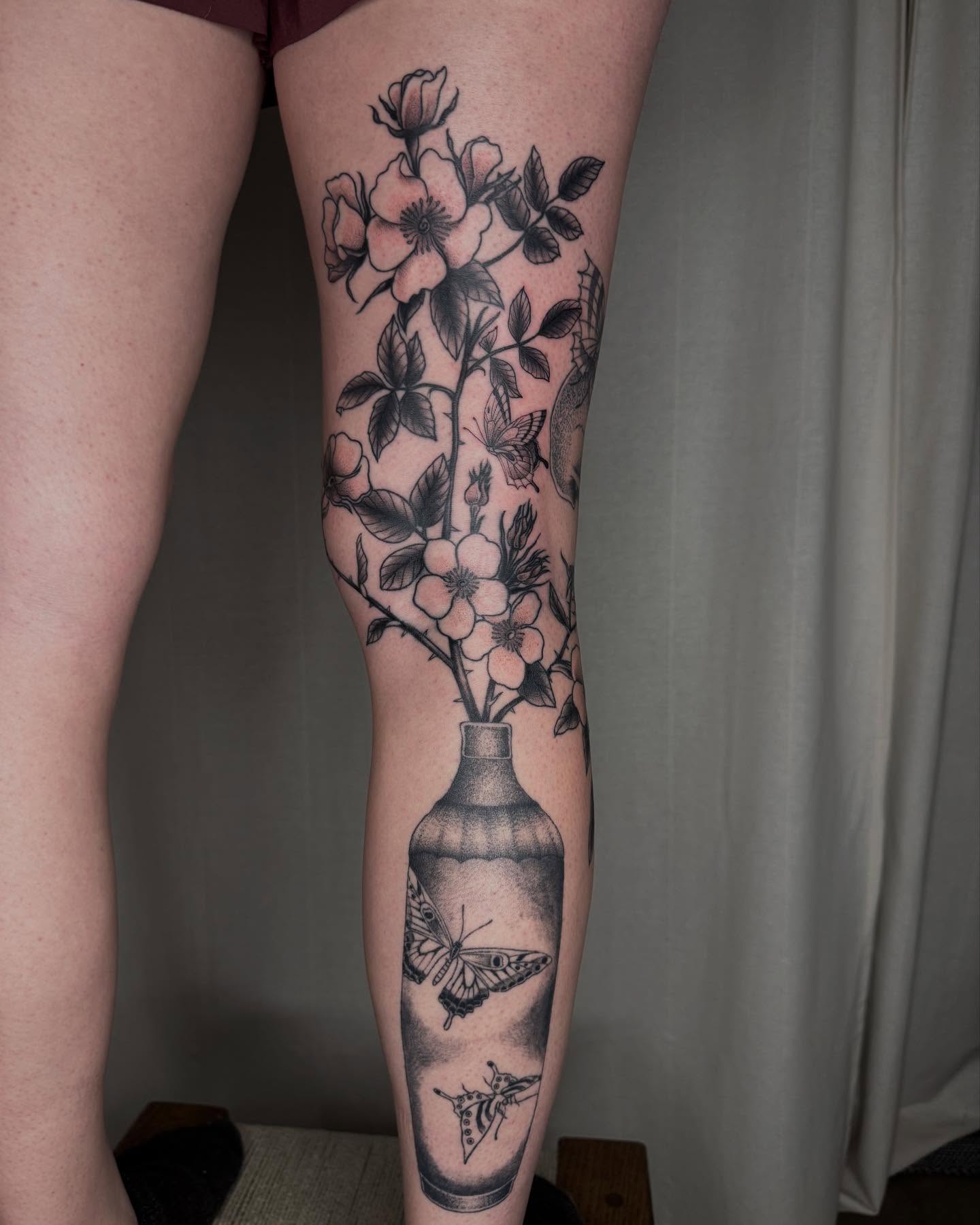 Flower arrangement black and grey tattoo on the calf by Finley Jordan