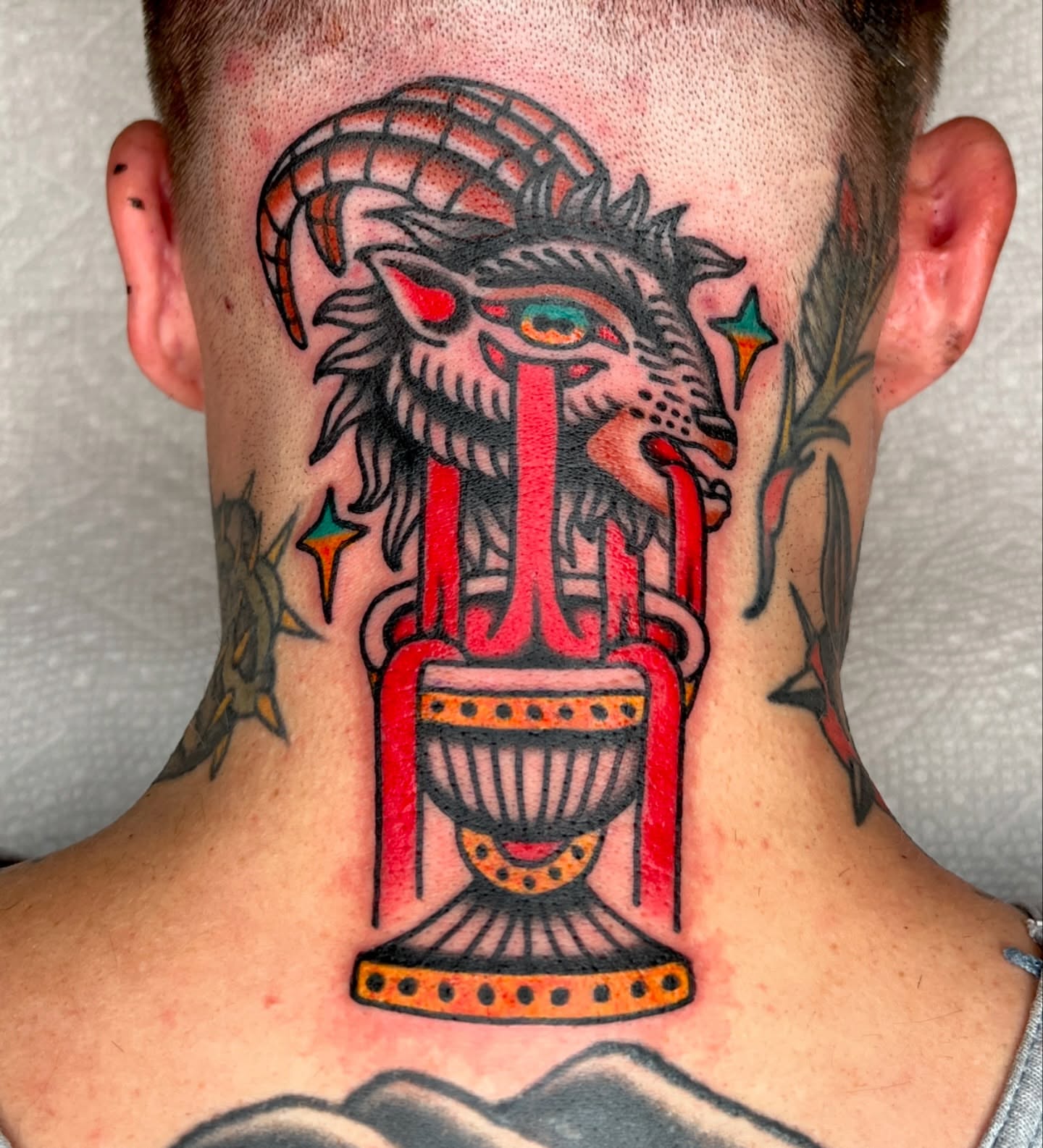 Goat-headed creature American traditional tattoo on the neck by Ian Jett